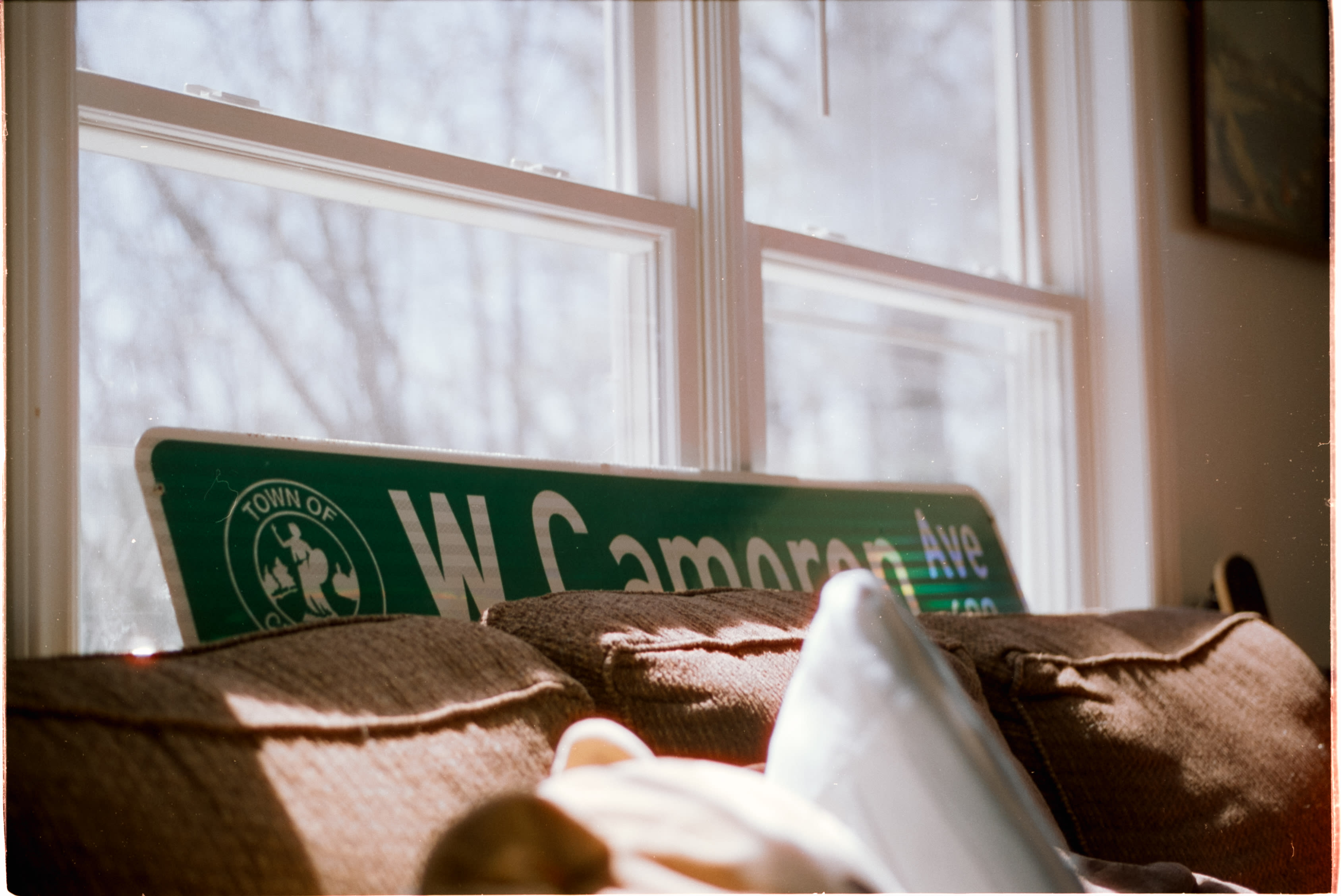 A W Cameron Ave street sign propped on a couch under a window