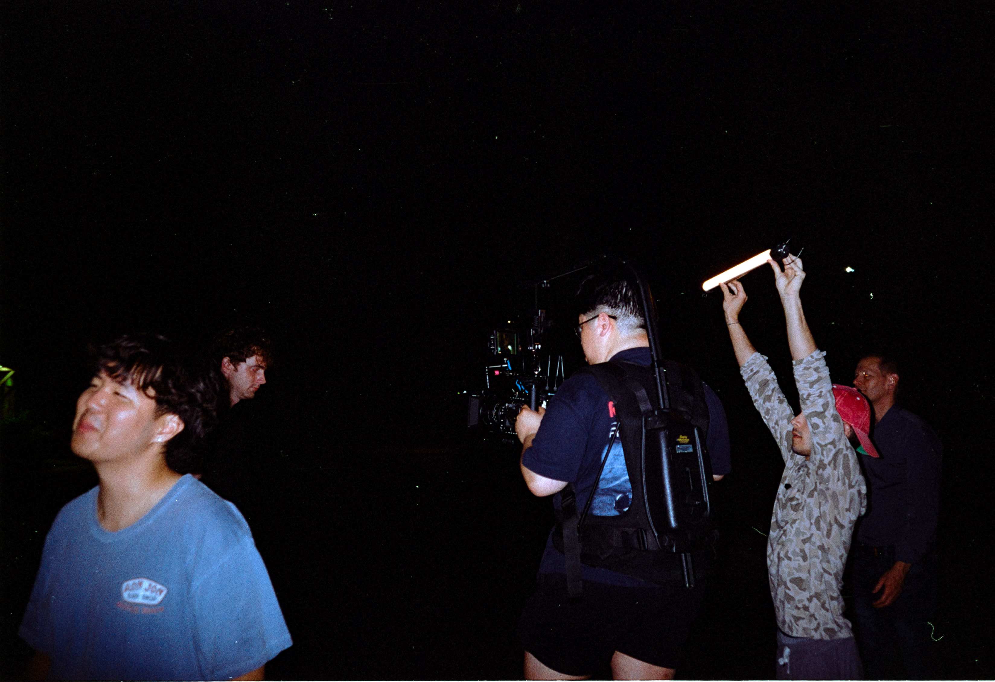 The crew filming at night, one of them holding up a light