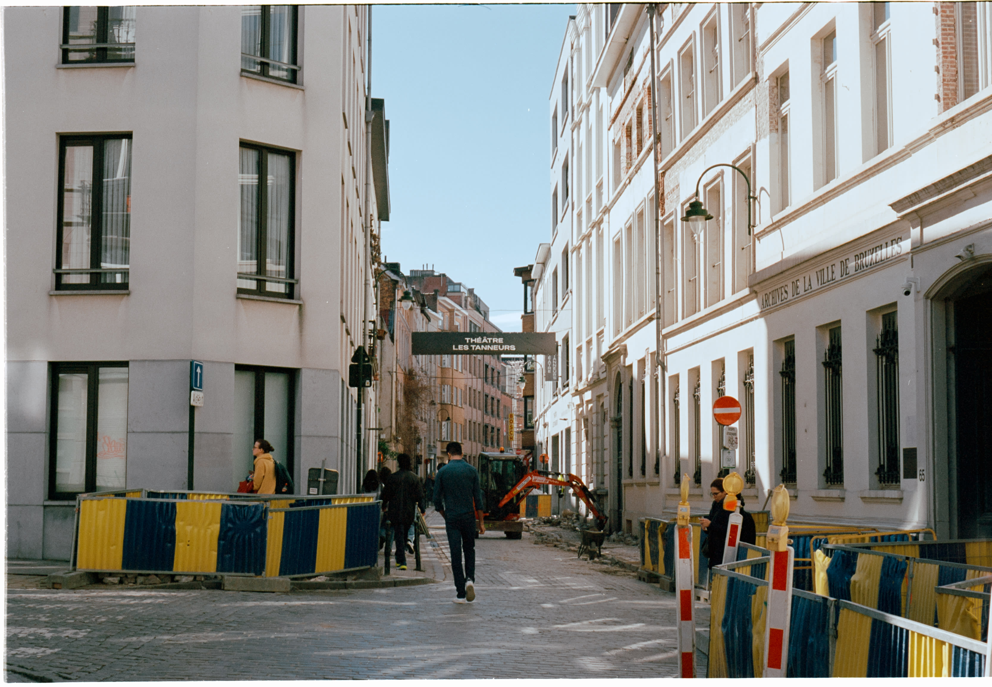 A side street lined with yellow and blue construction barriers