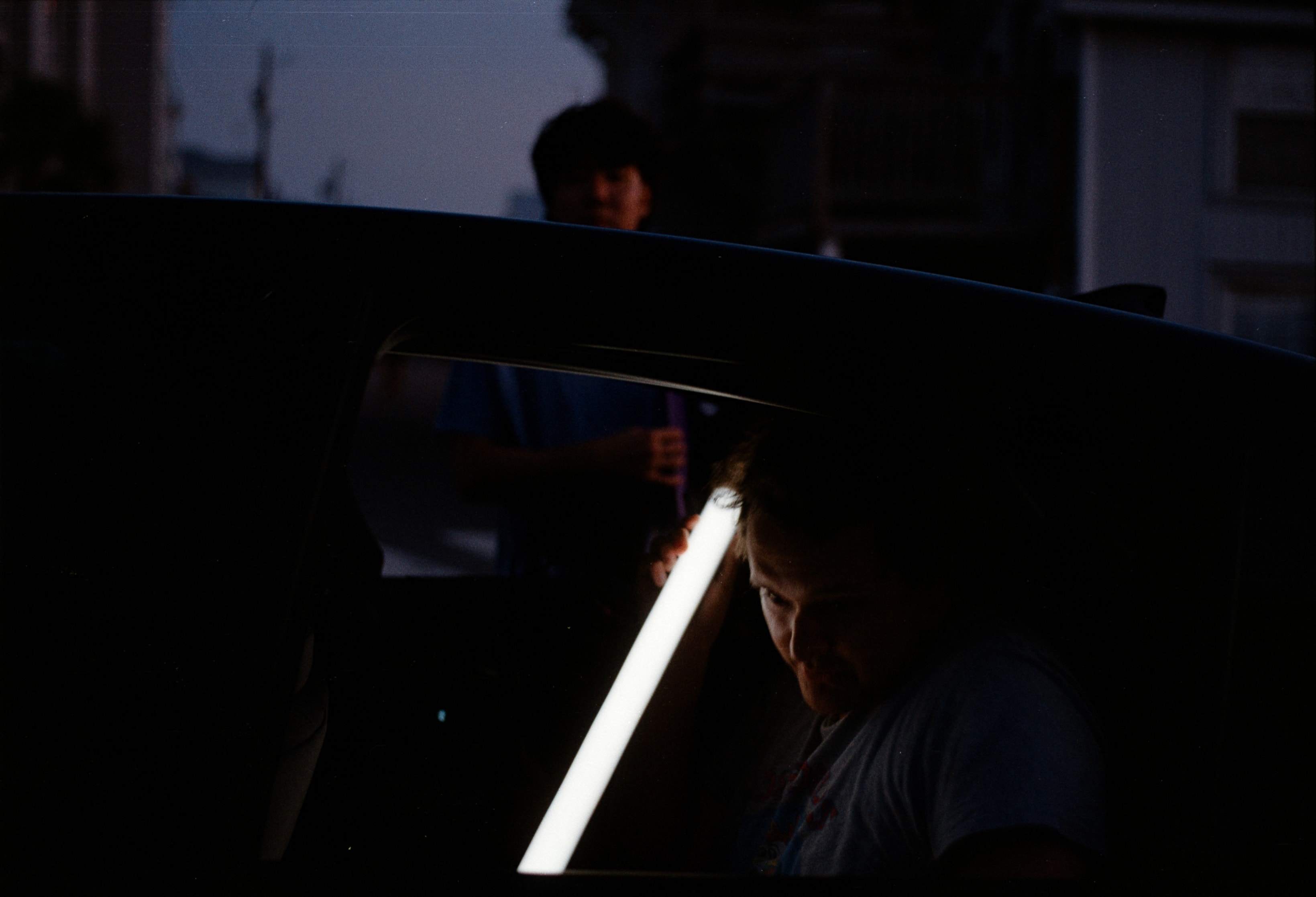 A face lit by a light tube through a car window at dusk