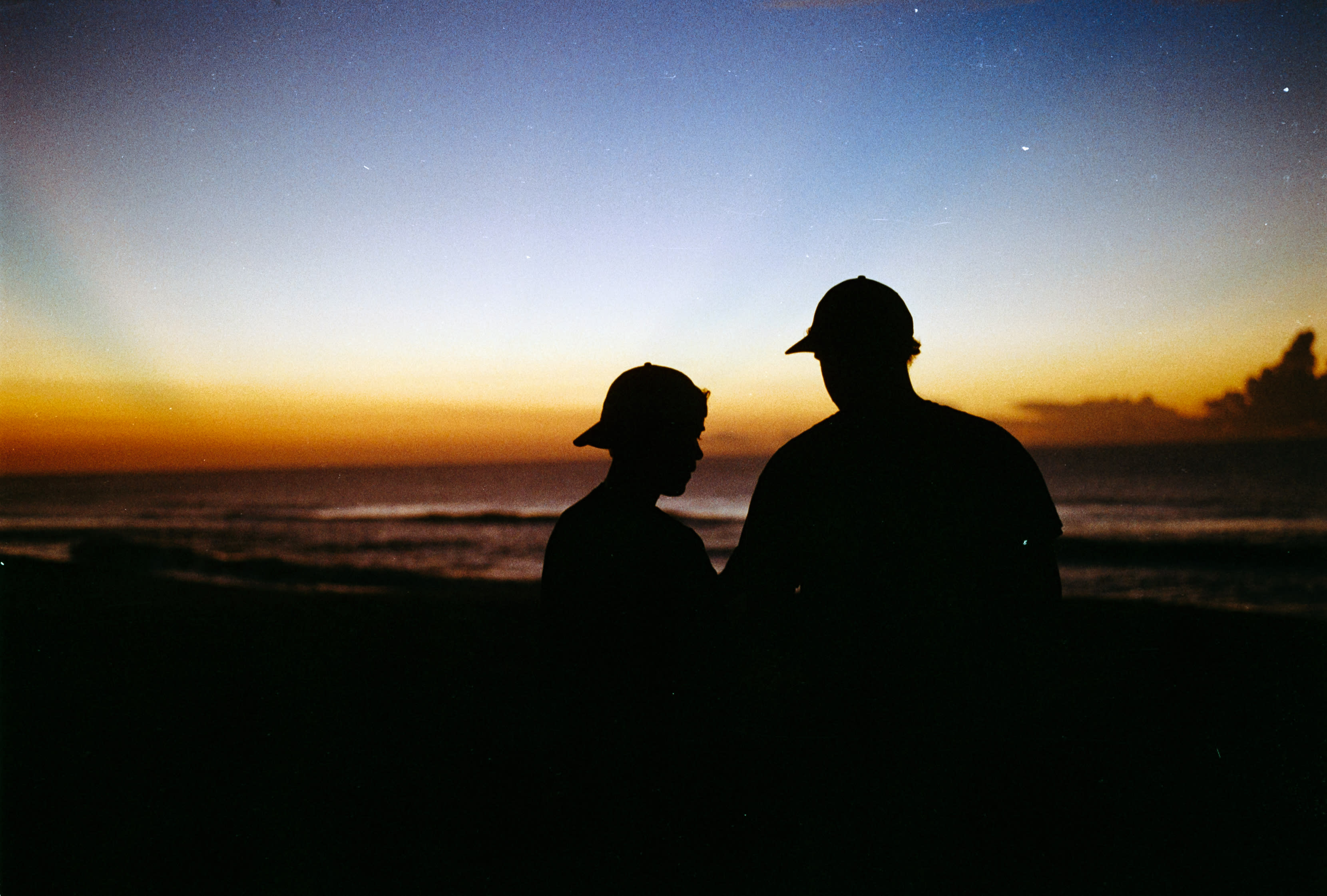 Two people in caps silhouetted against the sunset