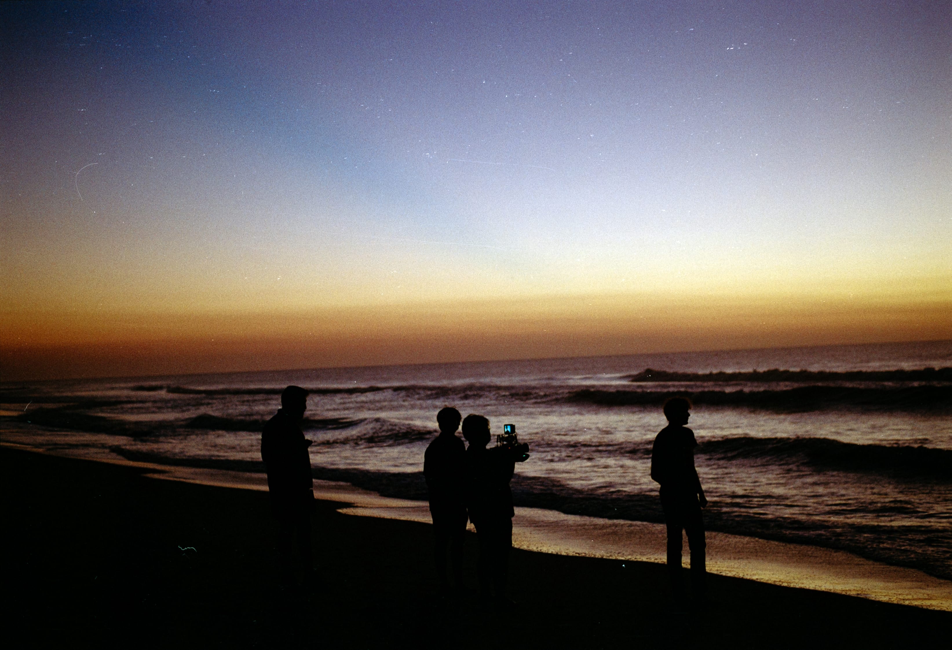 The crew standing in the surf at sunset