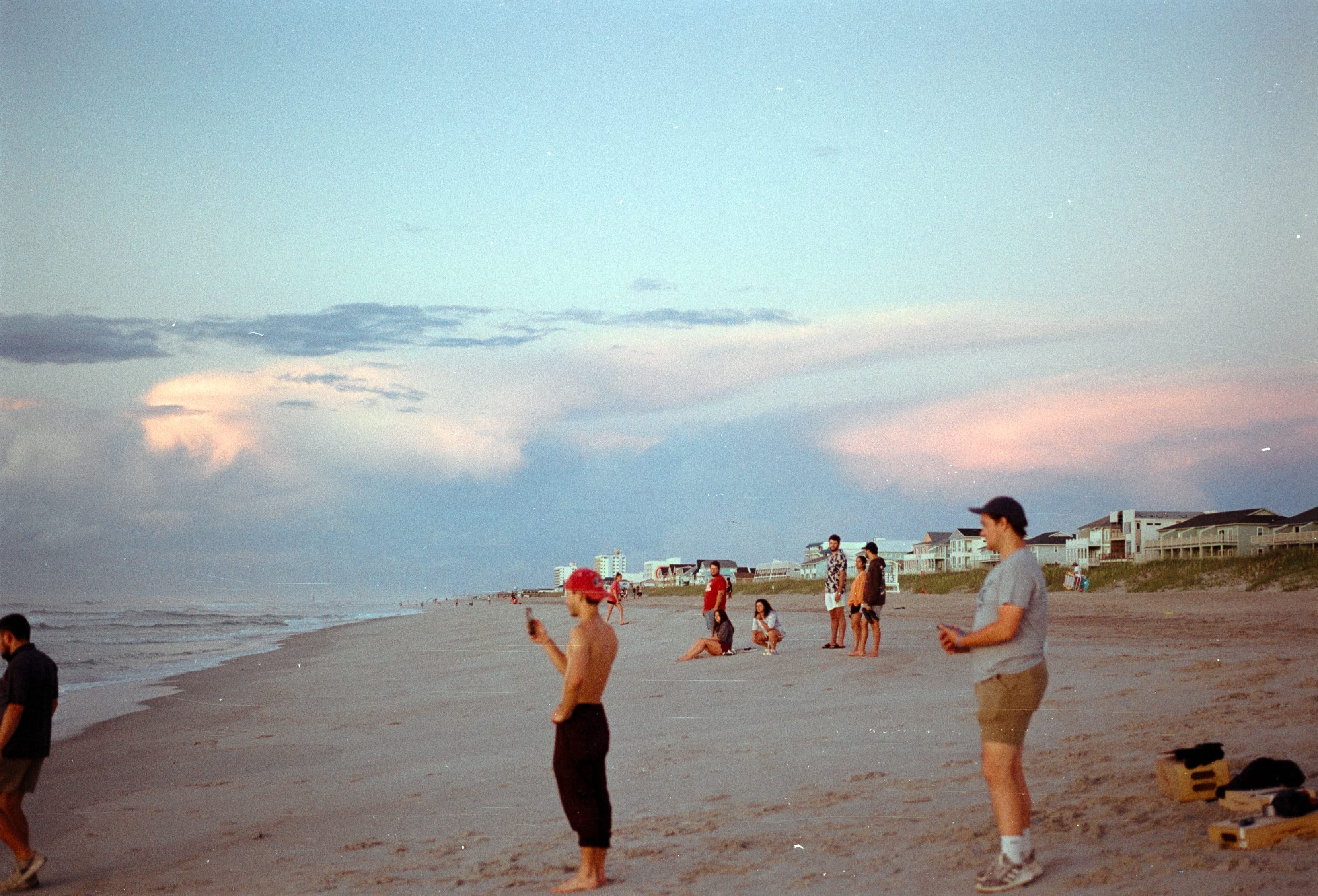 Cast and crew spread across a wide beach in the evening light