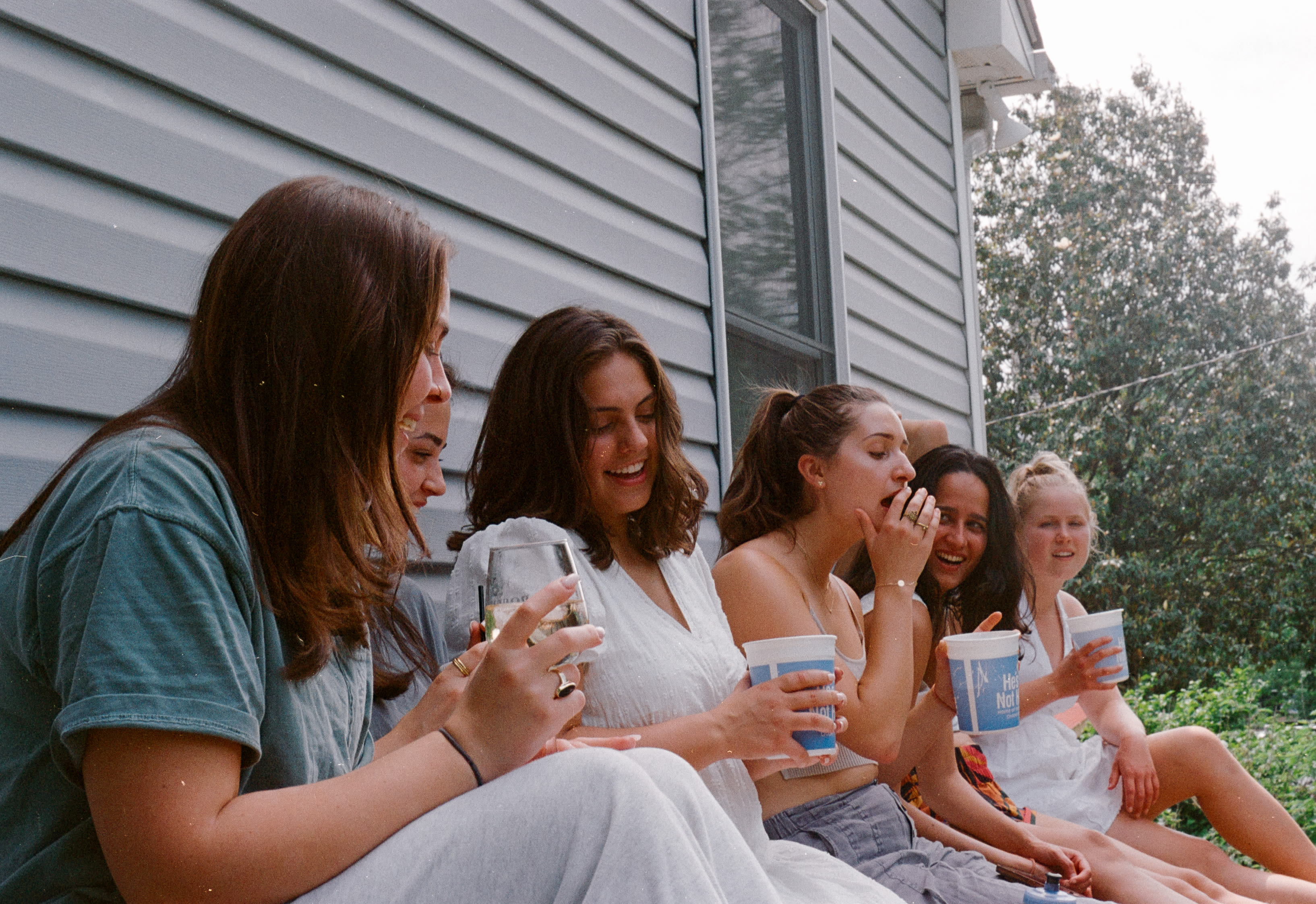 Friends laughing together beside a gray house