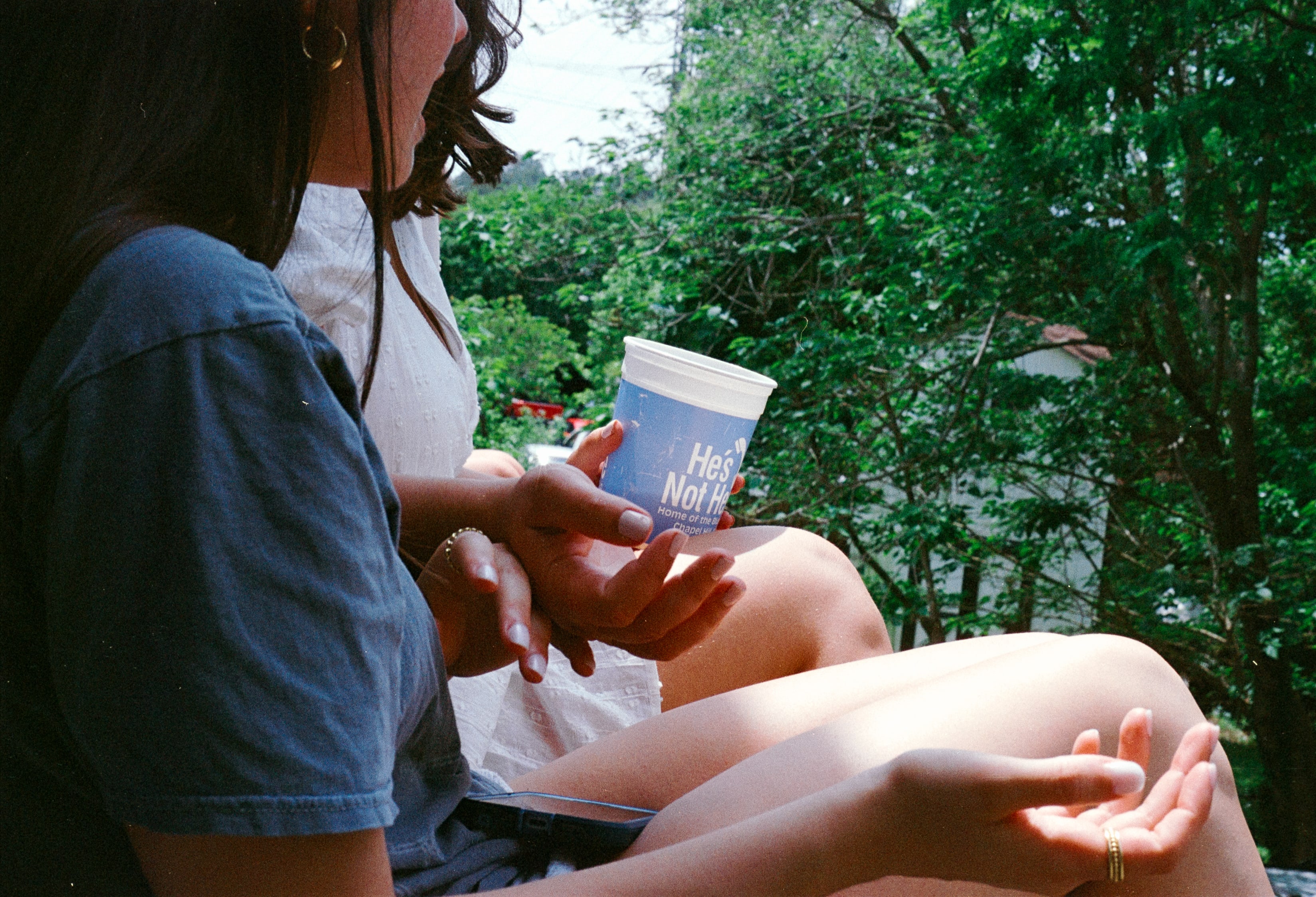 Hands and a paper cup in the afternoon sun