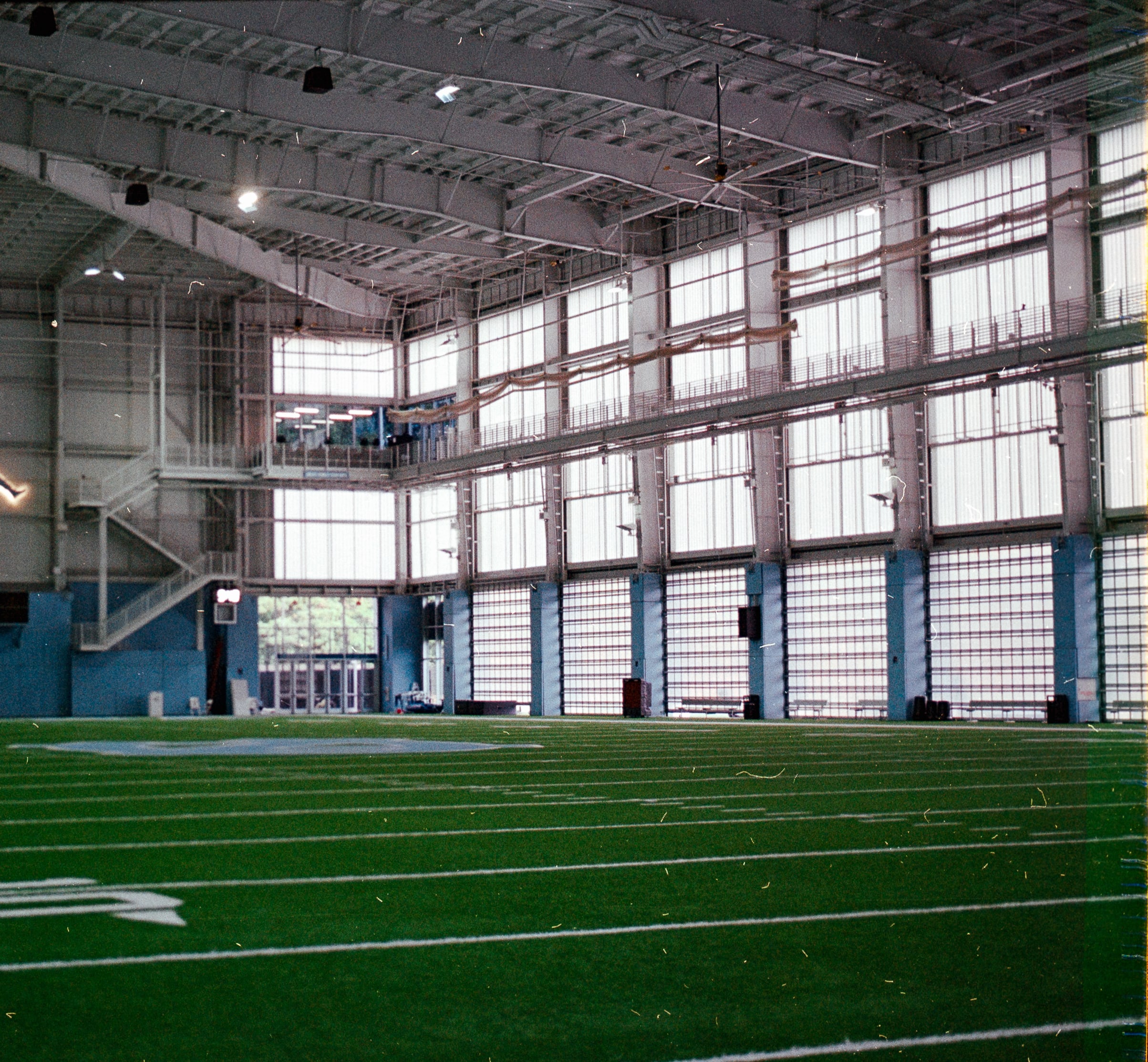 An empty indoor football practice field with tall windows