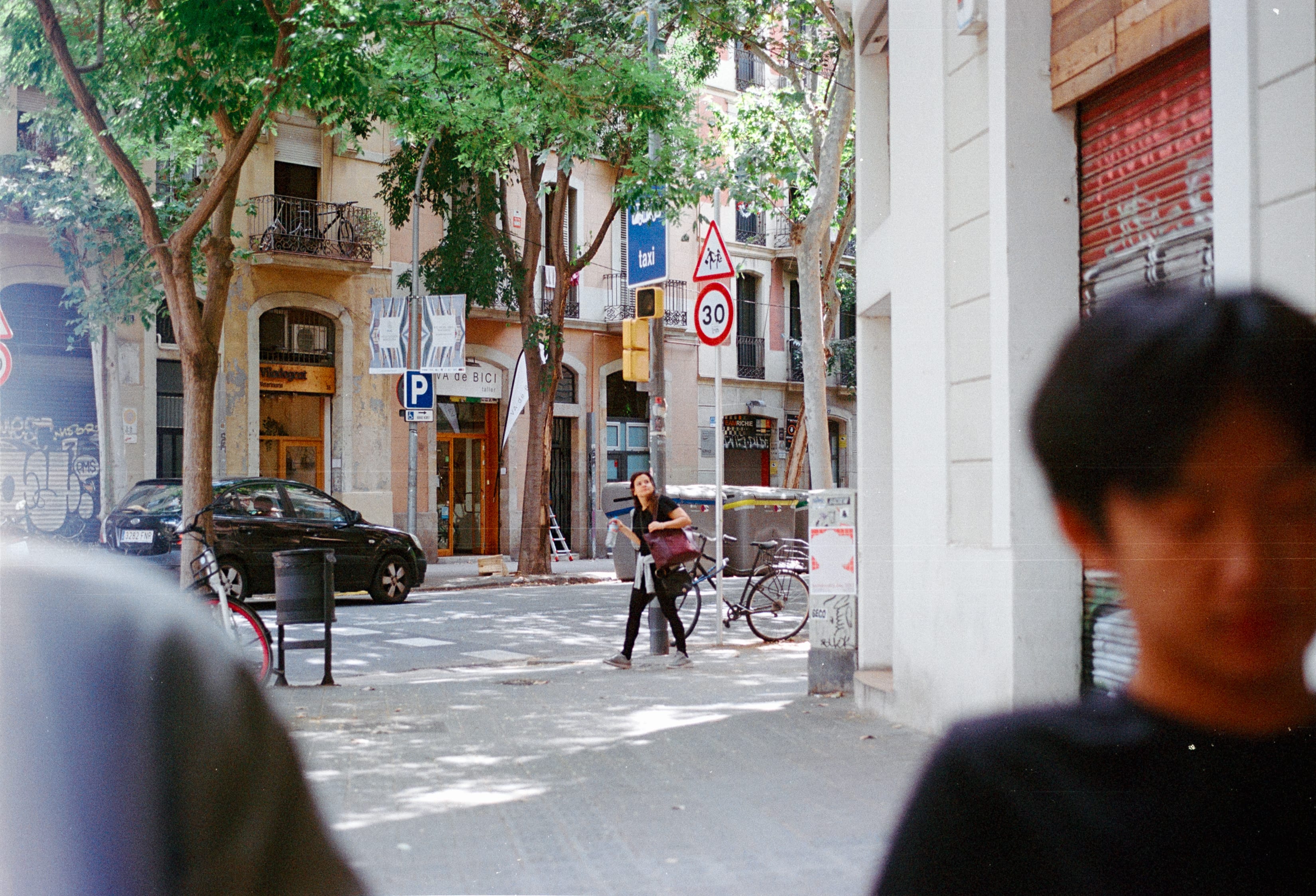 A friend in the foreground of a sunny street corner