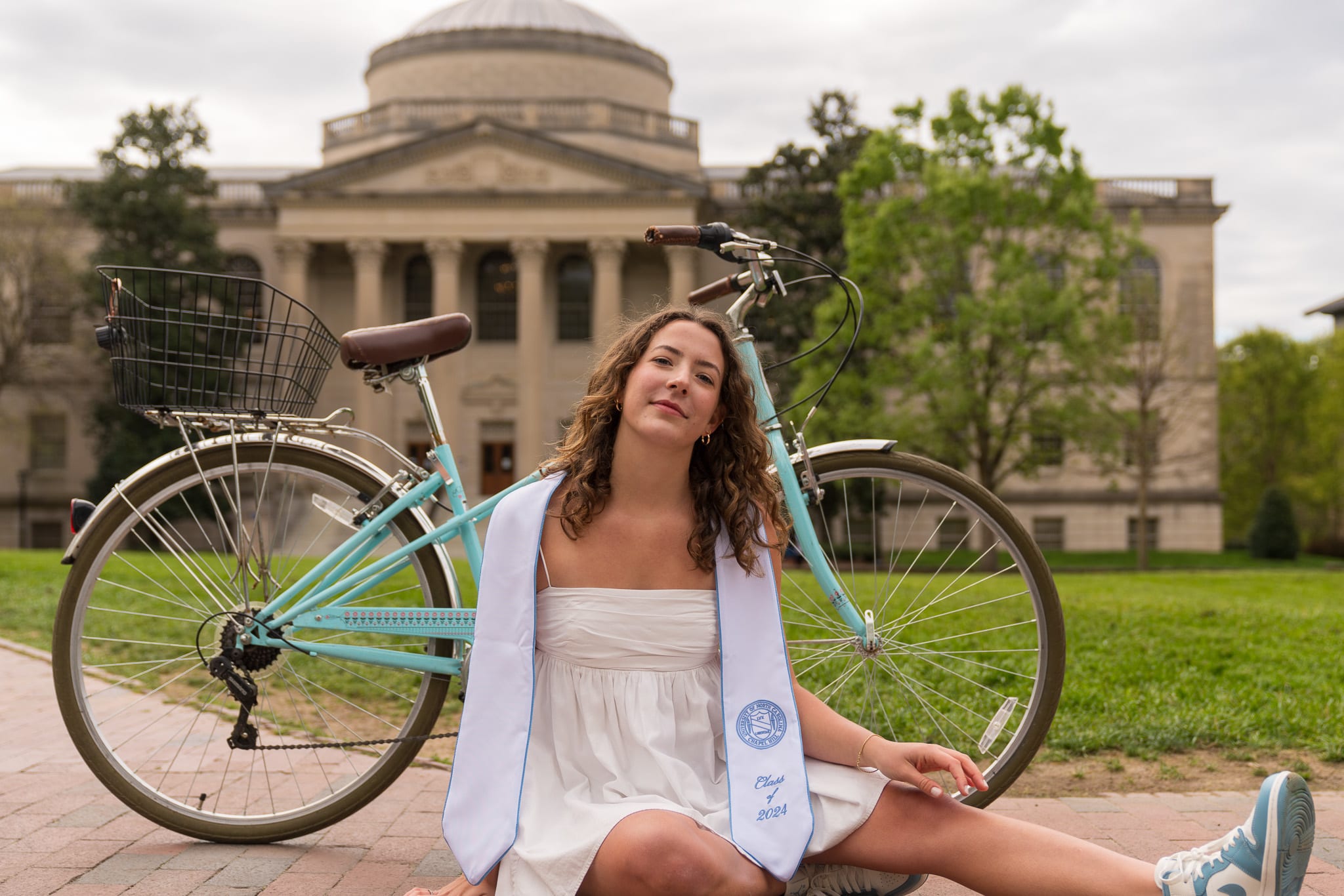 Grad sitting in front of her bike by Wilson Library