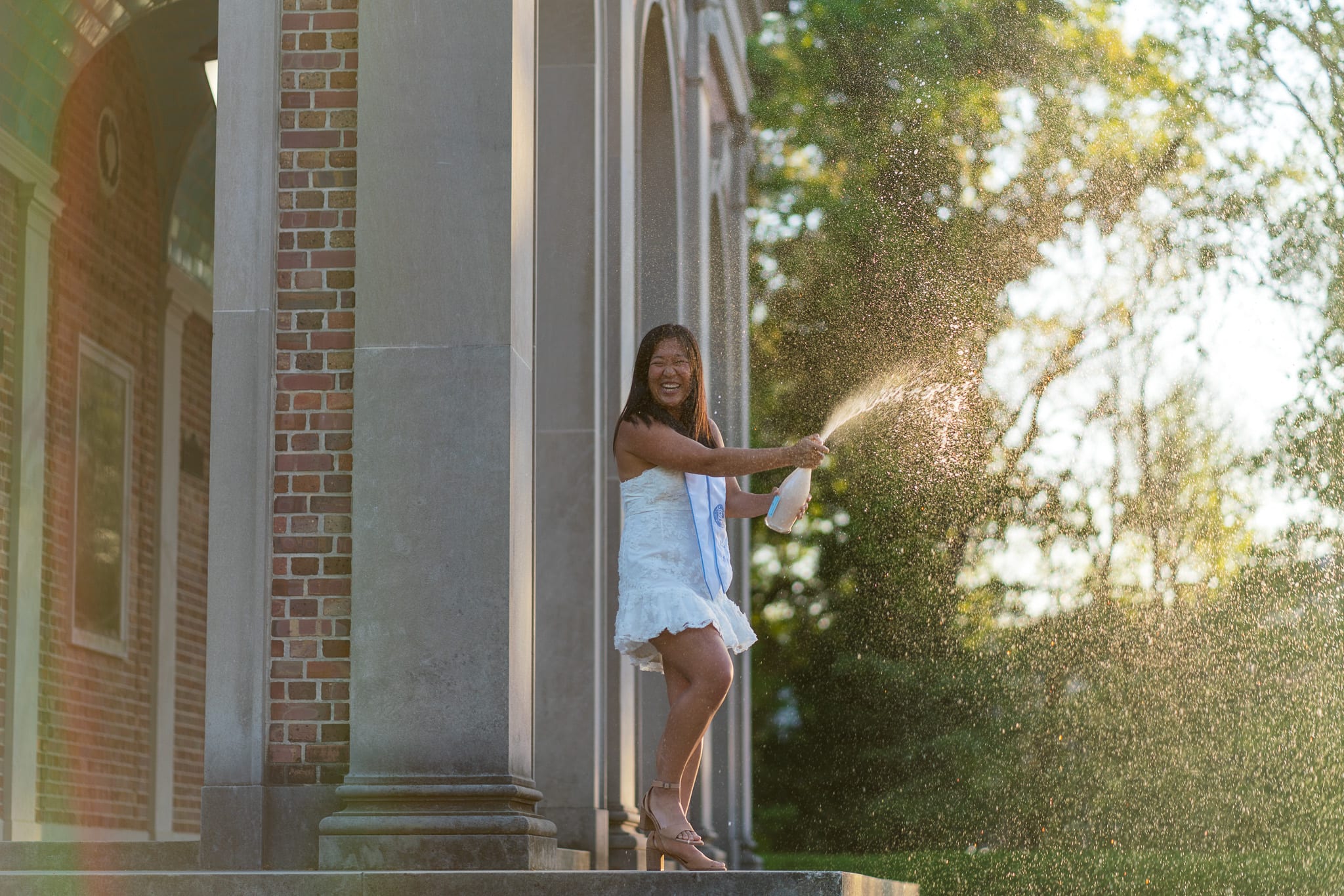A grad popping champagne in front of the Bell Tower