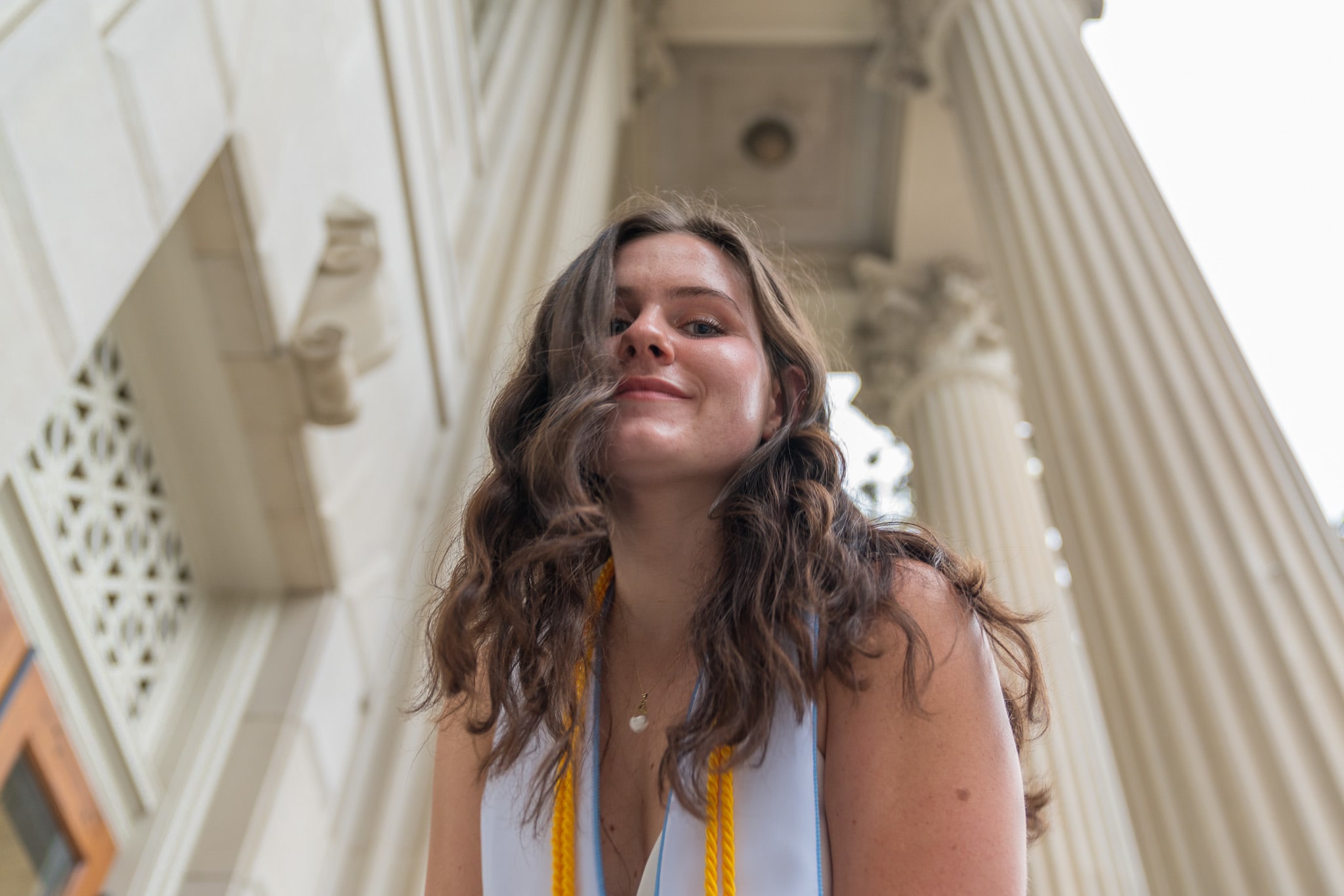 A grad leaning down with Wilson Library in the background