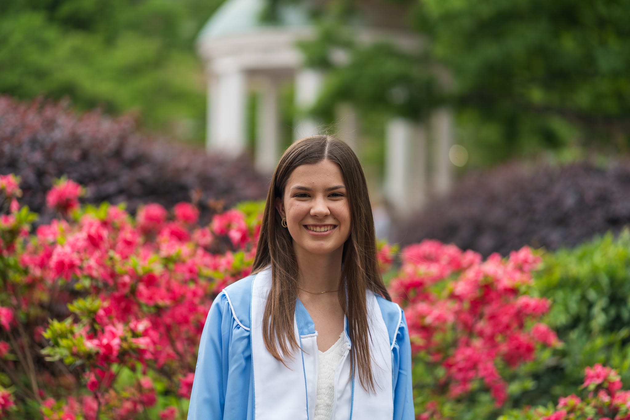 A grad in front of flowers by the Old Well