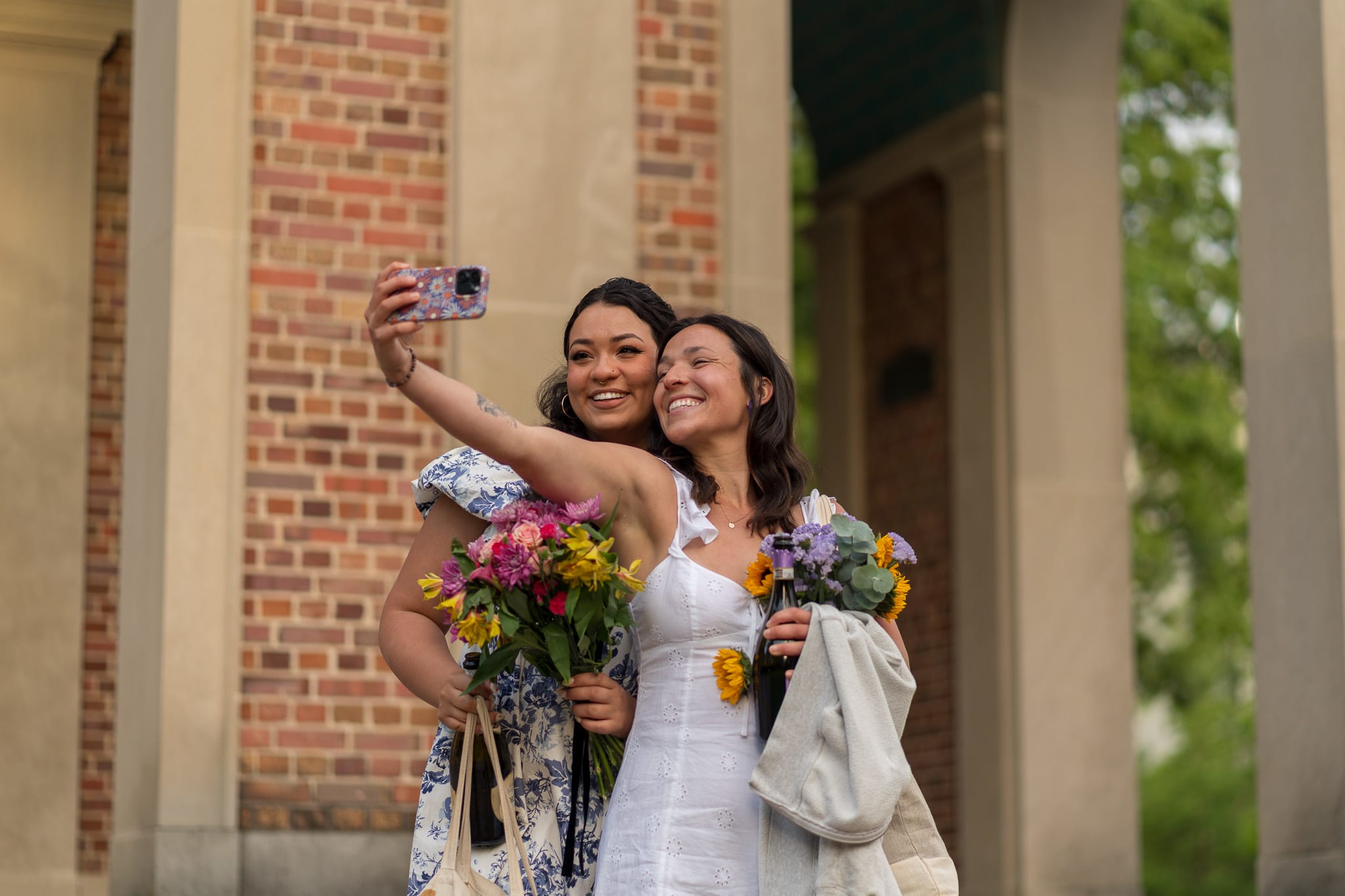 Two grads taking a selfie in front of the Bell Tower