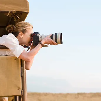 Guest photographing wildlife from a safari vehicle