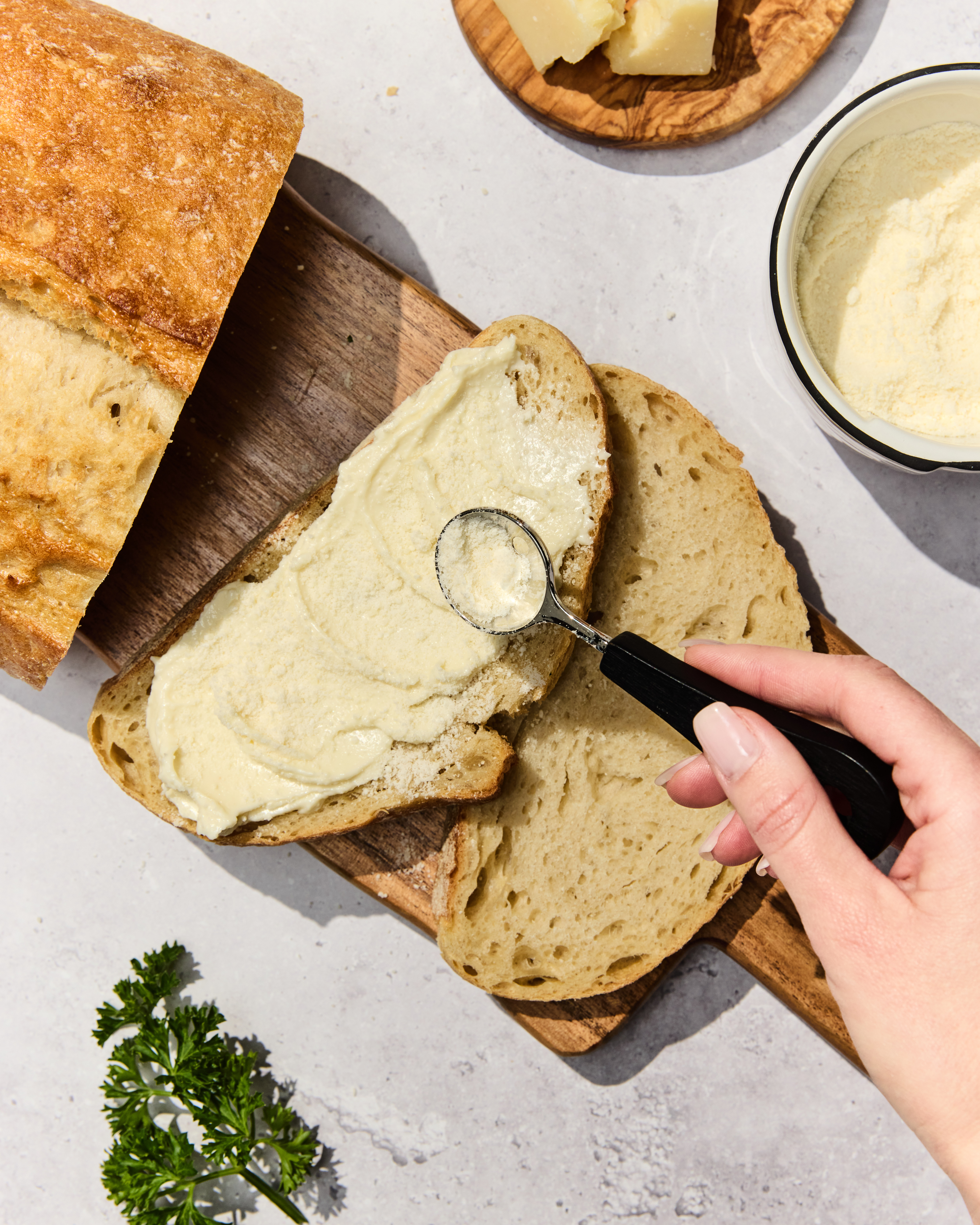 Sourdough bread with original garlic spread spread on thick and parmesan being sprinkled over the top