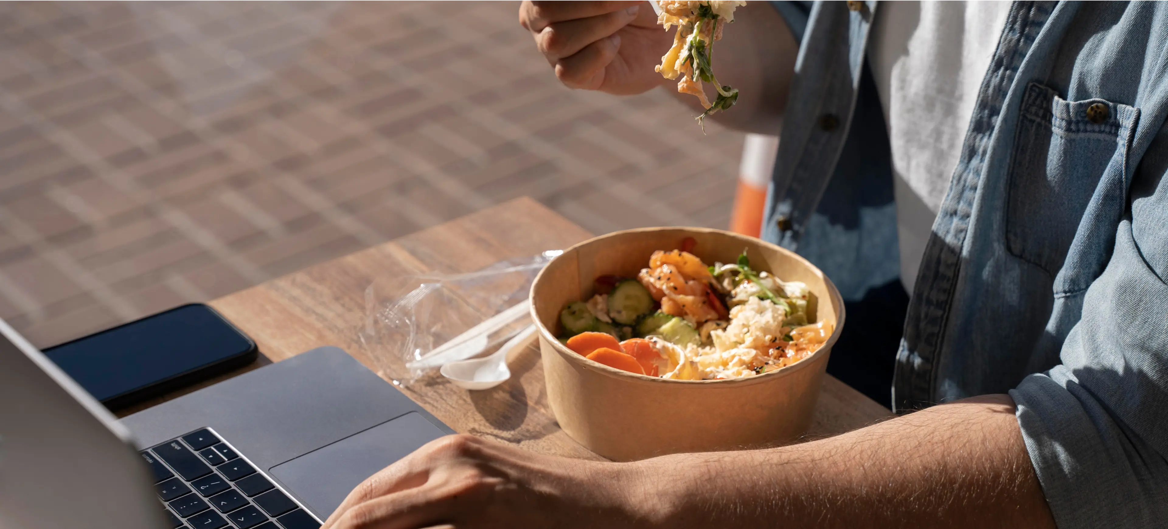 a man eating food and using a computer