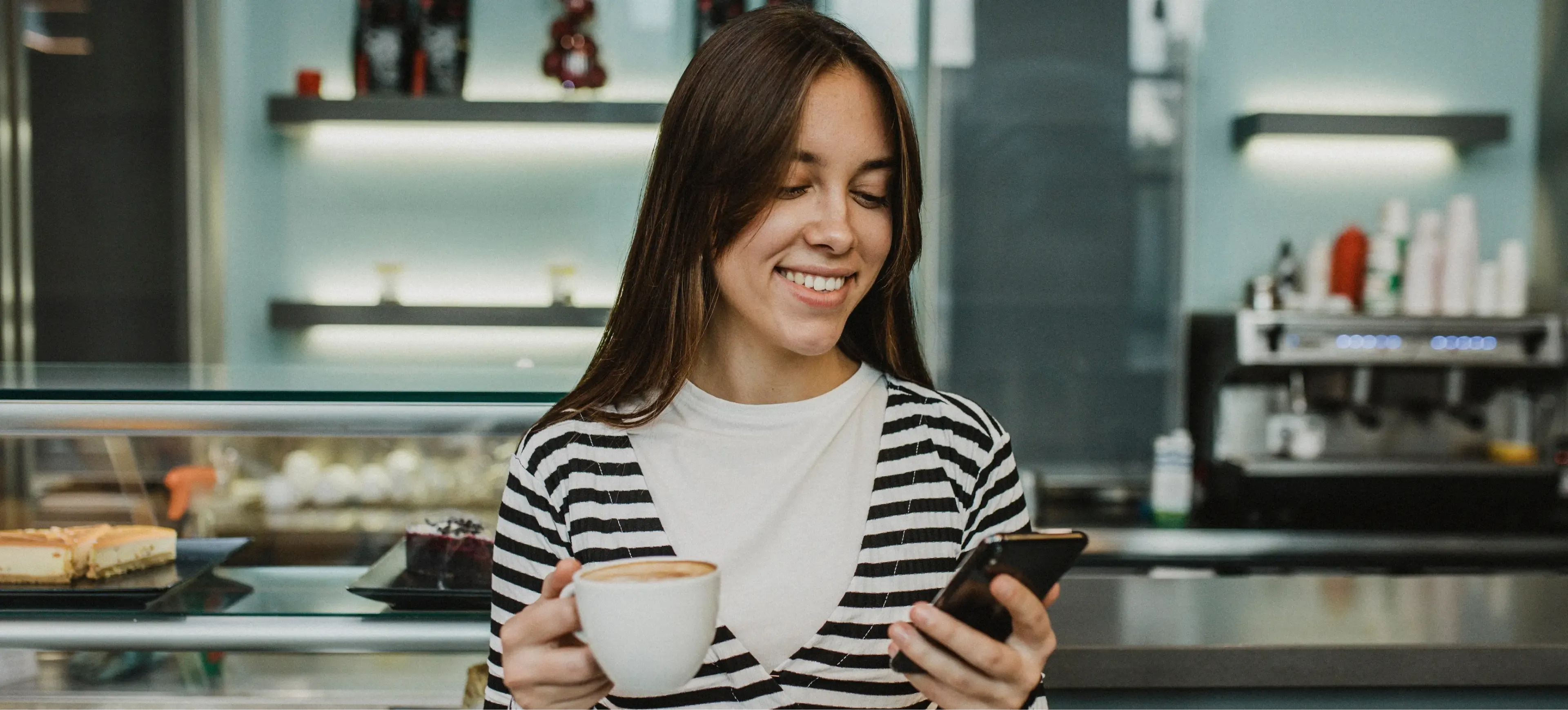 a woman ordering thru Crmb in a cellphone and drinking coffee