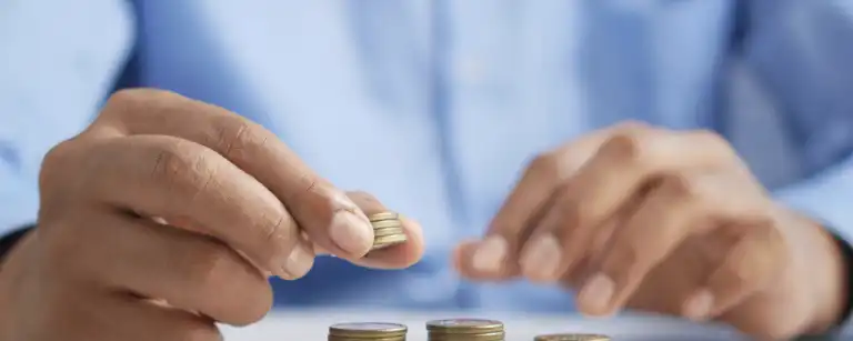 a man in blue shirt placing some coins in 3 columns on a table