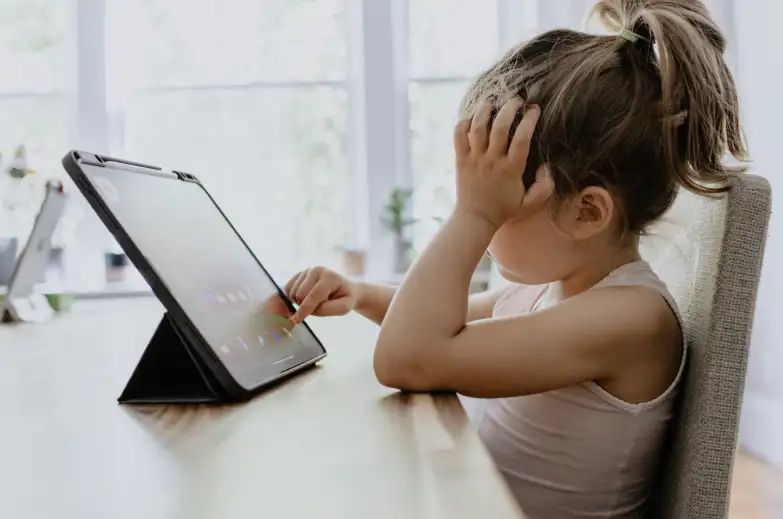 a young girl looking frustrated in front of an ipad