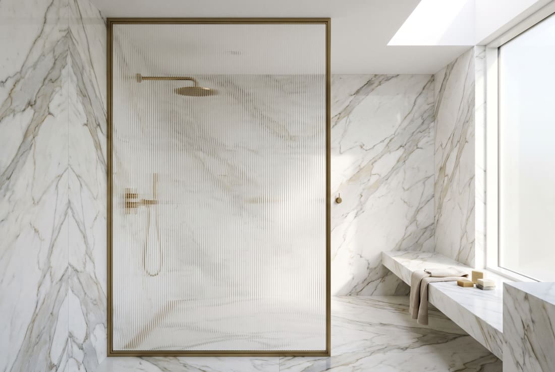 A book-matched marble wet room in bright, diffused light.