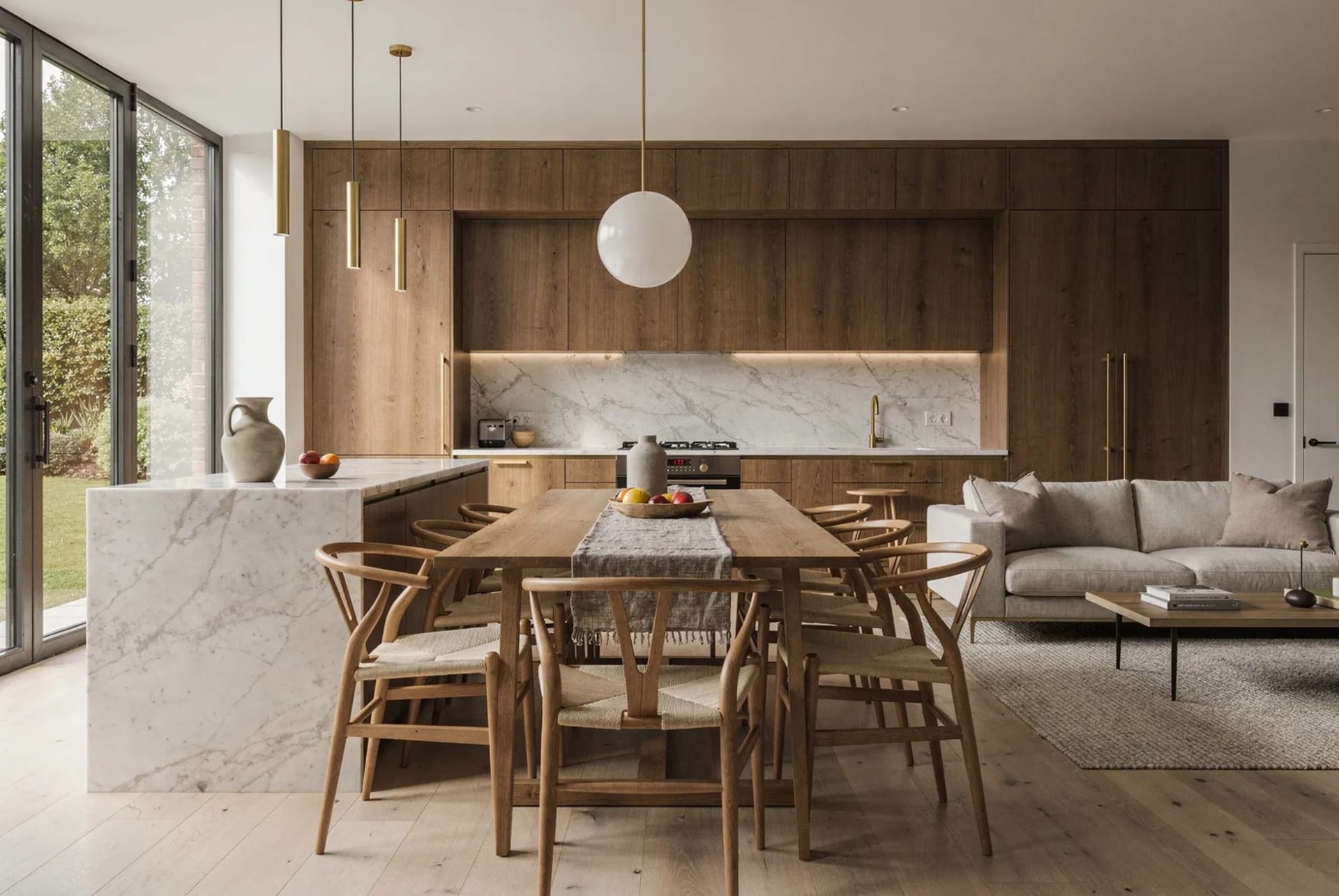An open-plan kitchen, dining and living room in warm timber and stone.