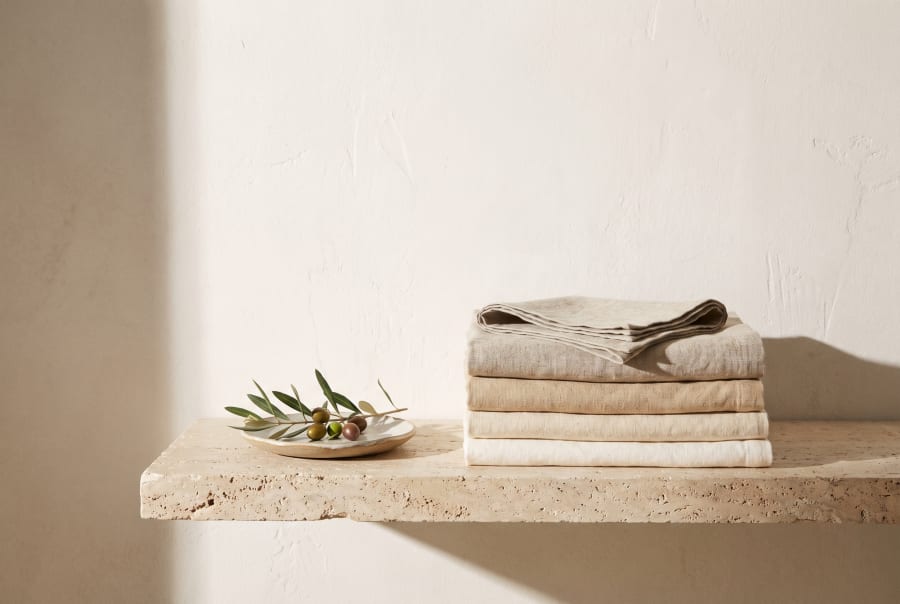 Folded linen towels on a travertine ledge.