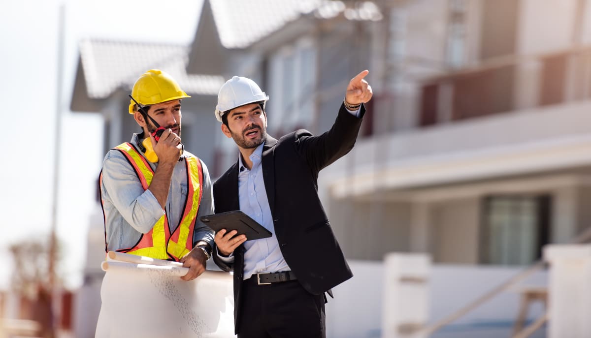 Ingenieros en obra revisando planos digitales con tablet