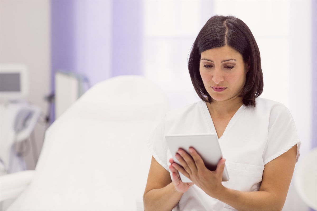 Dermatóloga revisando información de paciente en tablet en una clínica moderna