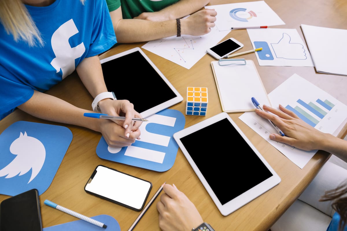 Equipo de marketing revisando campañas en tablet con íconos de redes sociales