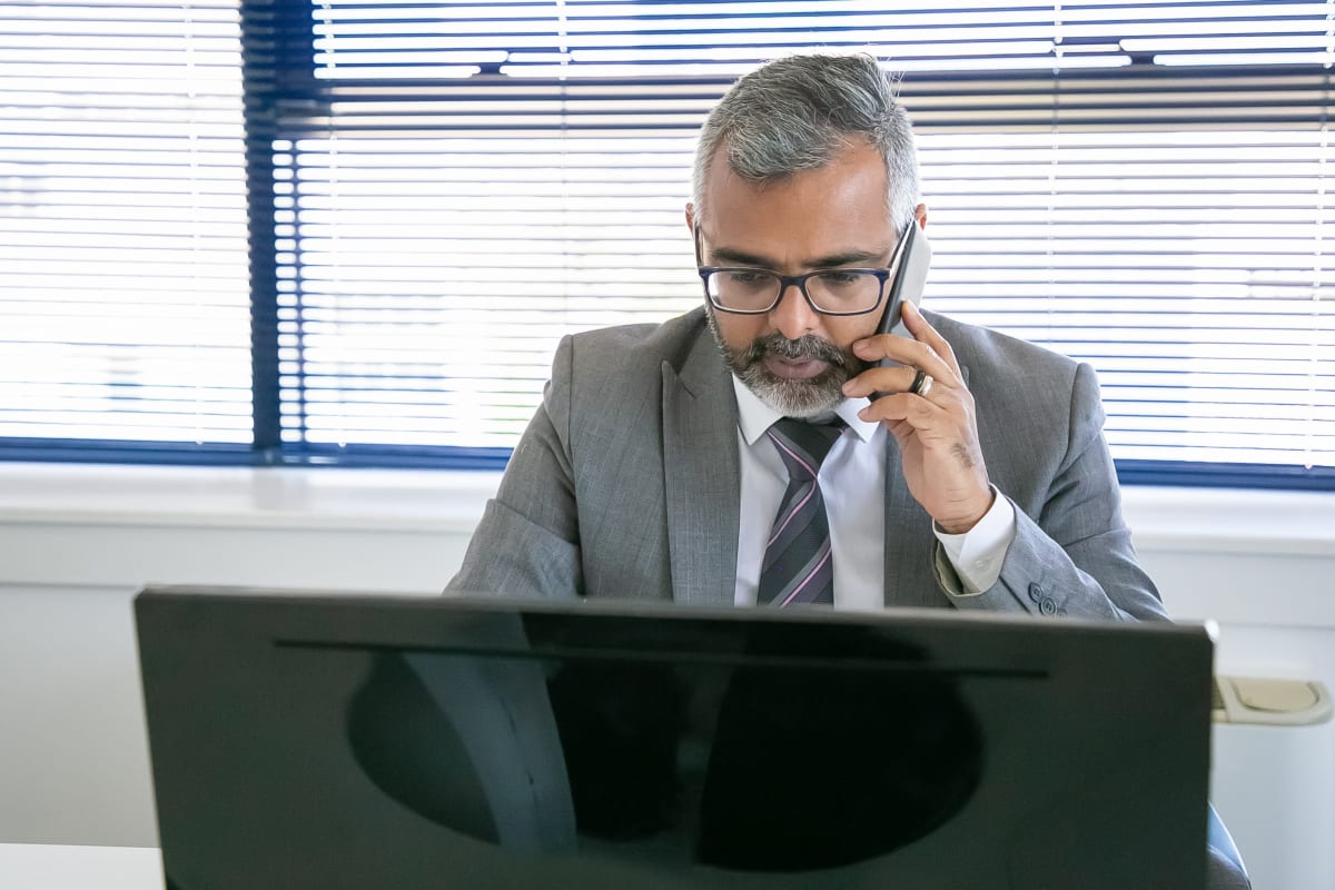 Ejecutivo respondiendo a un prospecto desde su computador y teléfono en la oficina