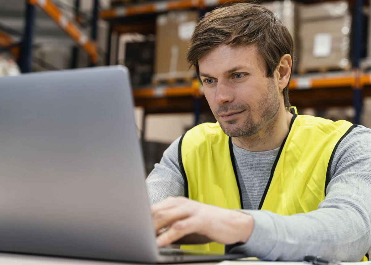 Coordinador de operaciones logísticas trabajando con un computador portátil dentro de una bodega