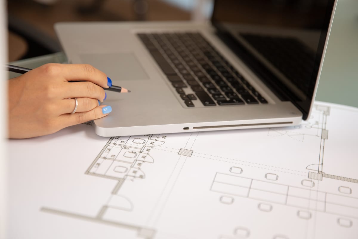 Laptop sobre planos de construcción en un escritorio de trabajo