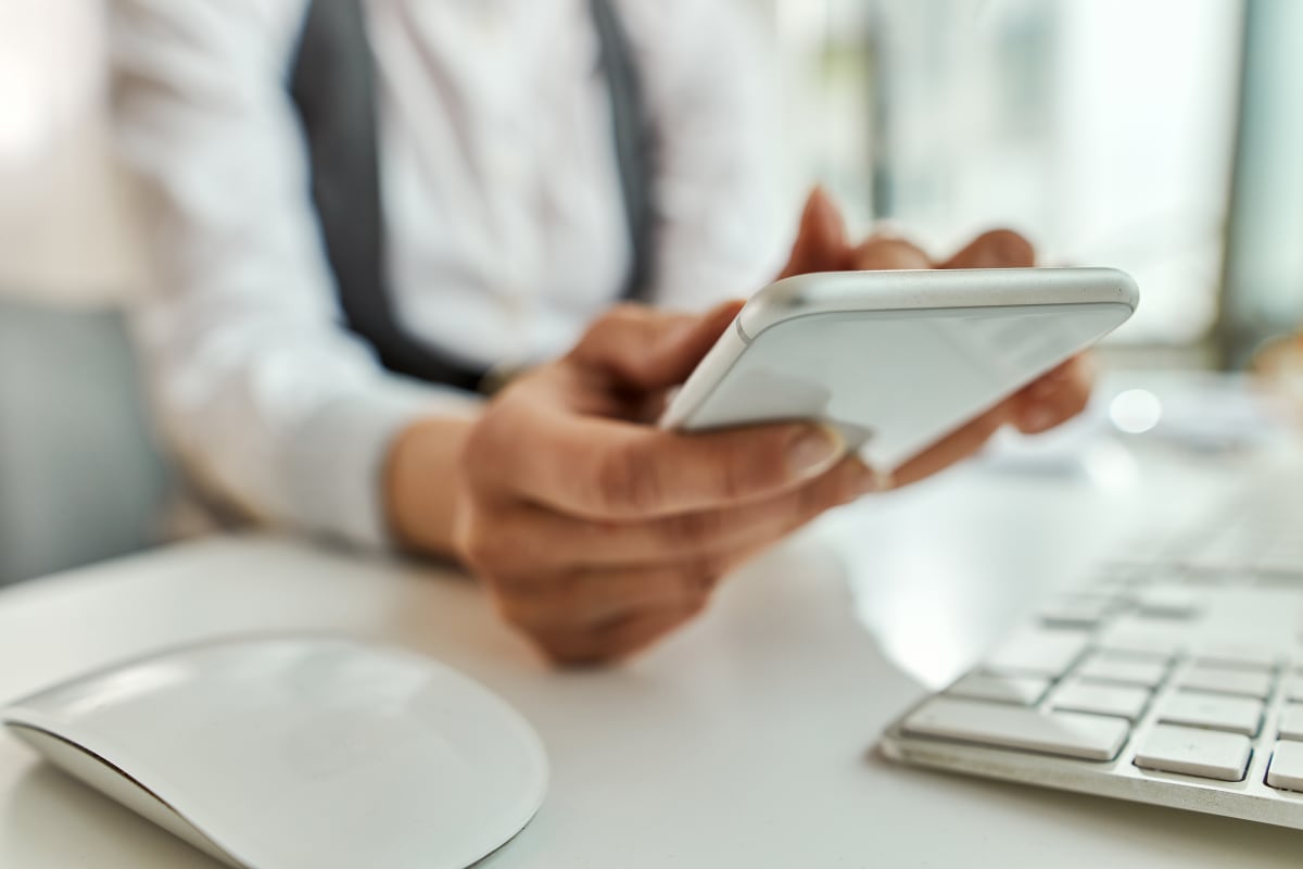 Persona respondiendo mensajes desde su teléfono en una oficina