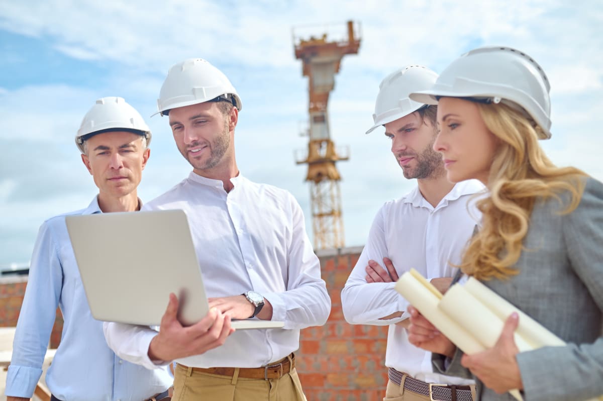 Ingeniero de construcción mostrando un proyecto a sus colegas en una laptop