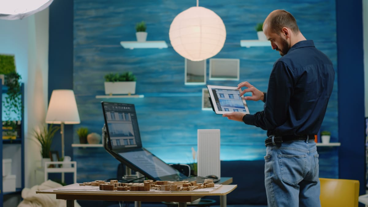 Ejecutivo comercial inmobiliario revisando planos en tablet en oficina de arquitectura