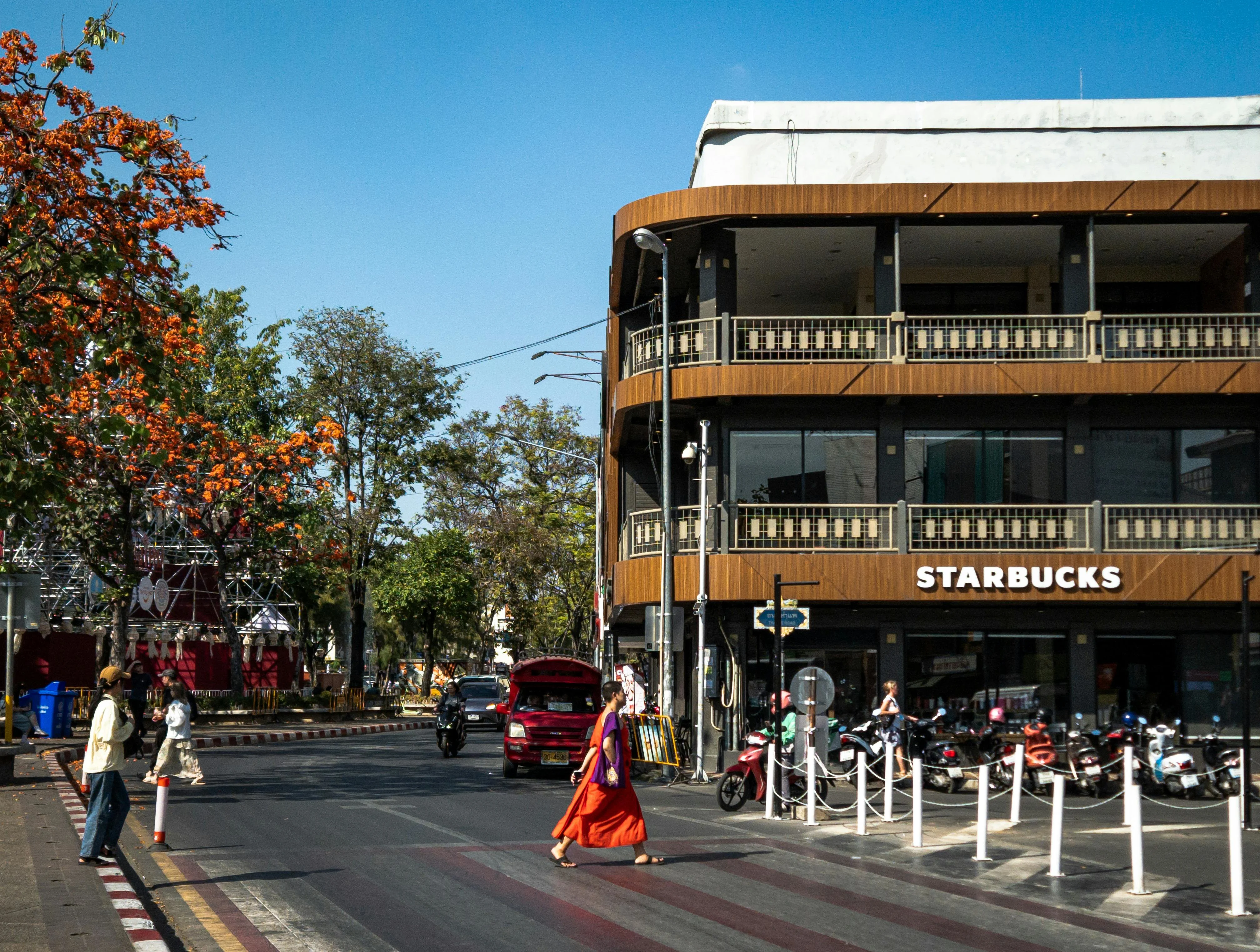 Bustling street in Chiang Mai with a Starbucks and pedestrians crossing in daylight.