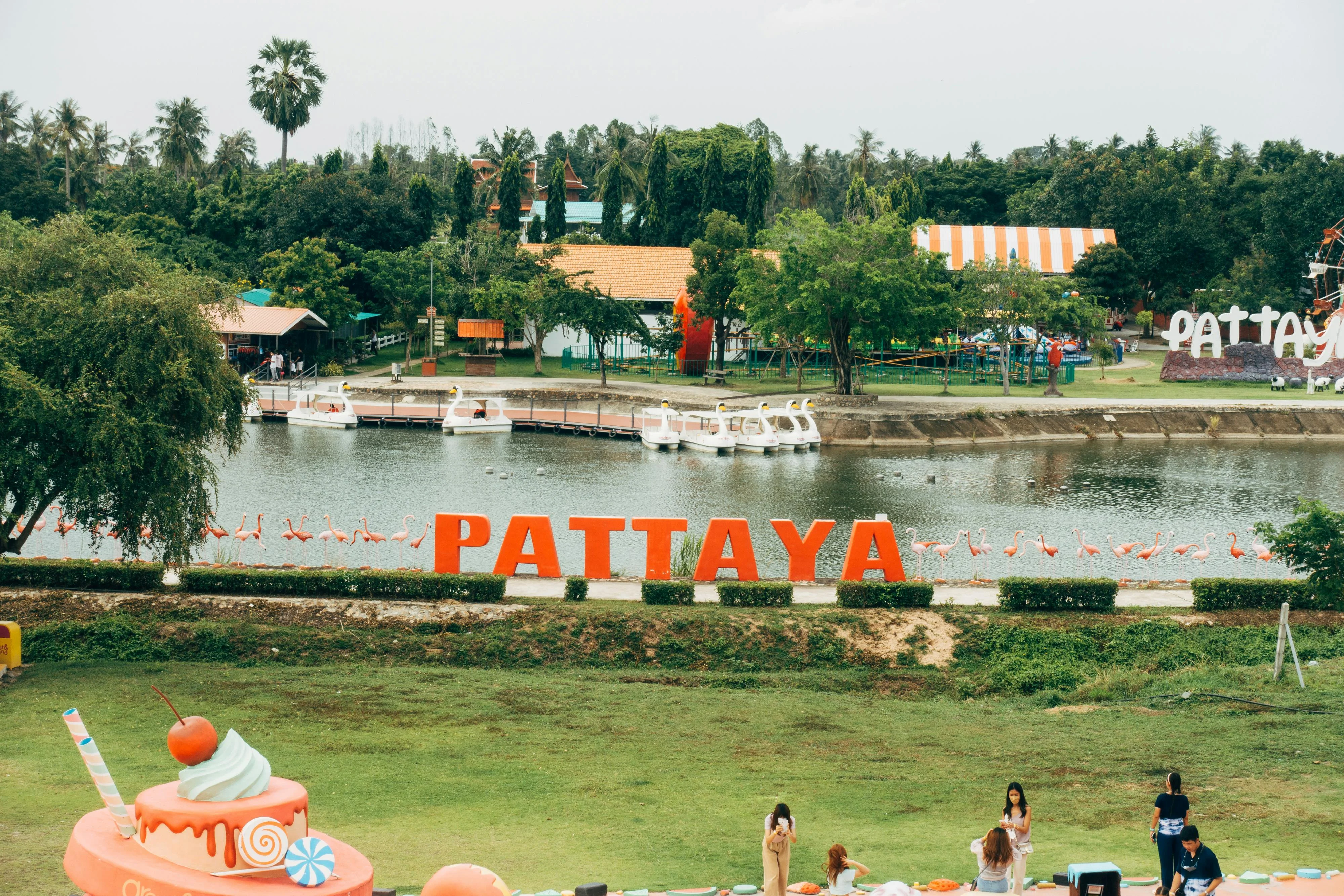 A vibrant scene in Pattaya, Thailand with a lake, iconic sign, and colorful decorations