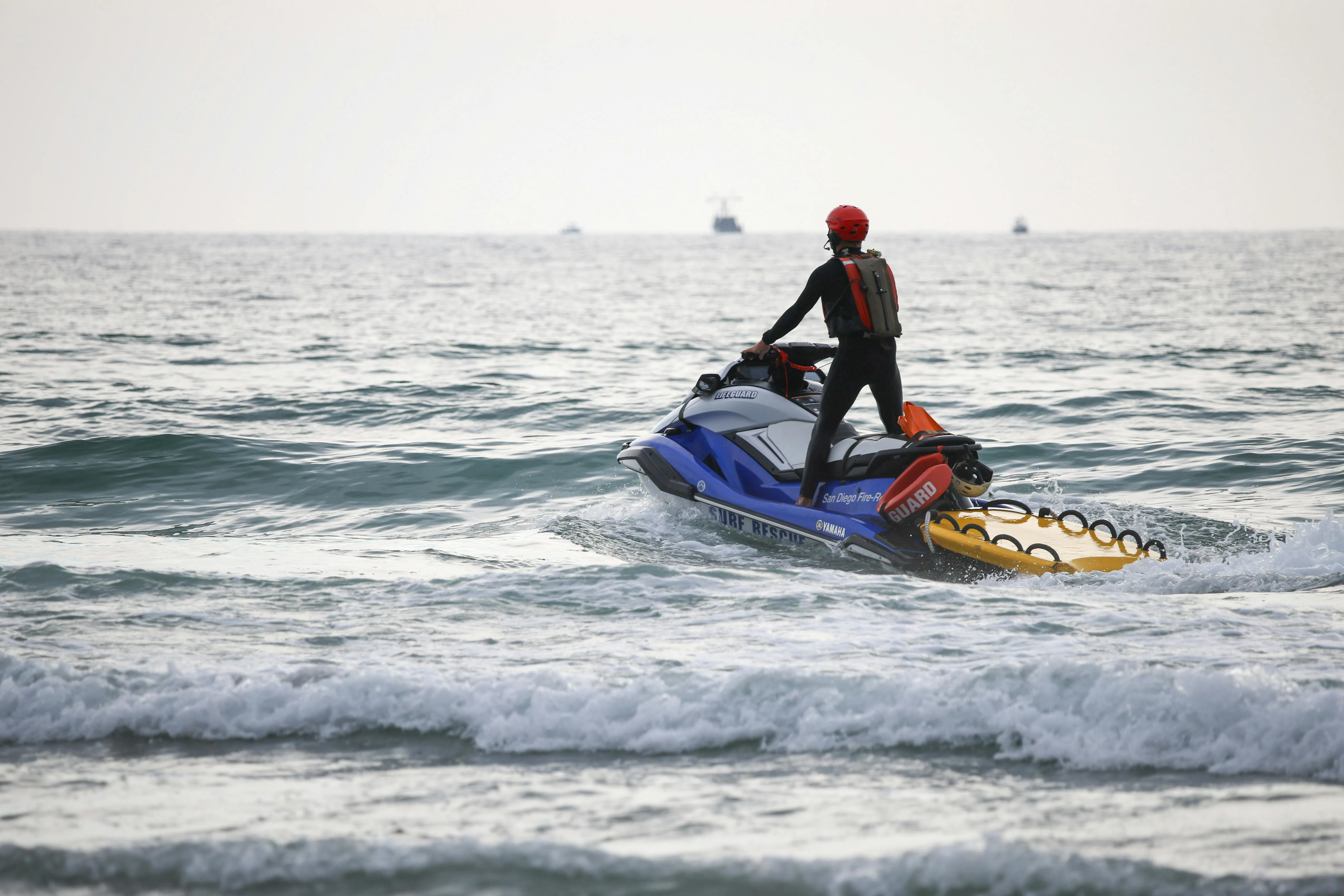 A lifeguard on a jet ski patrols the ocean to ensure swimmer safety during daytime