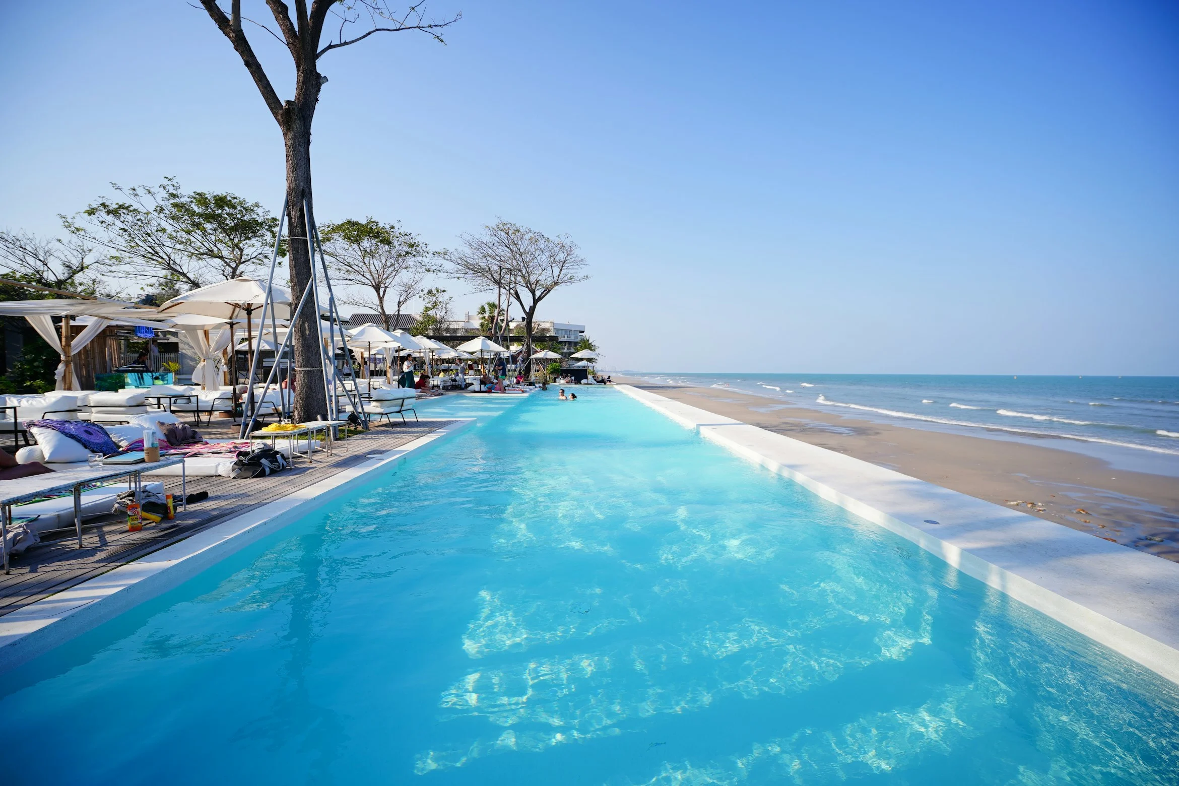 During summer in Hua Hin, Thailand, sip iced coffee at a beachside bar and gaze at the endless horizon, a refreshing and tranquil experience by the sea.