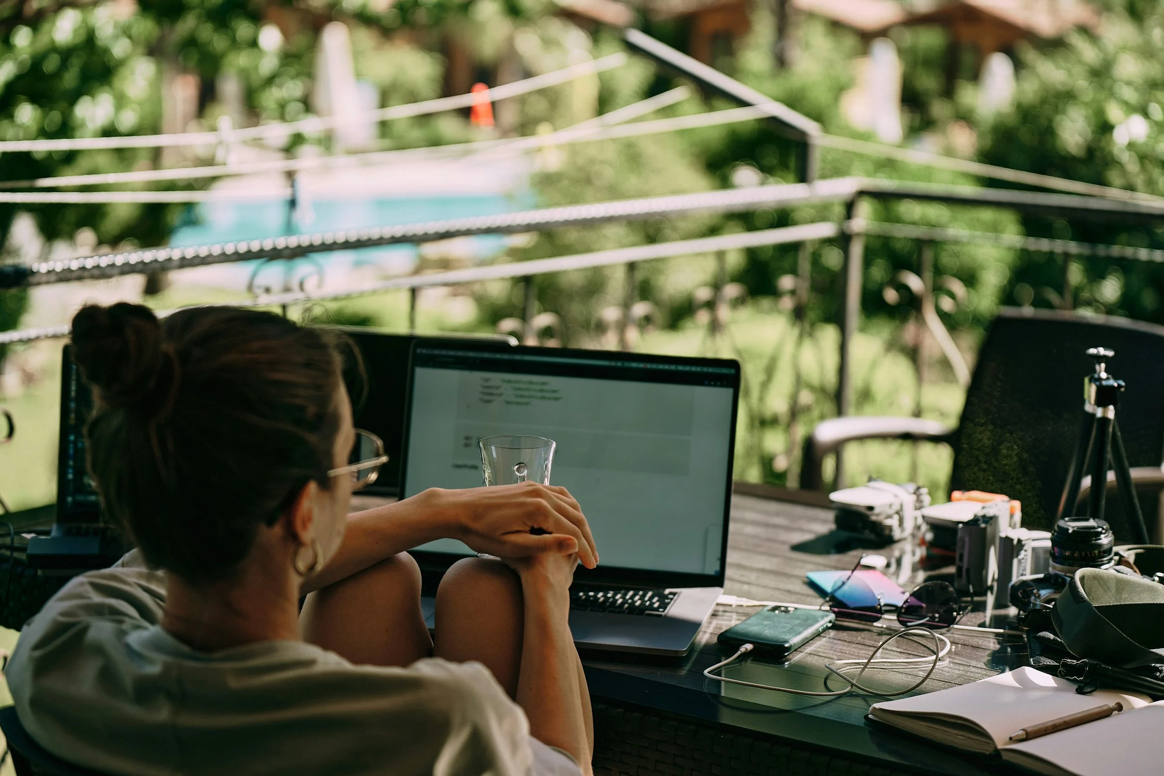 A girl working on the table on the terrace. Many laptops and other staff. Back view