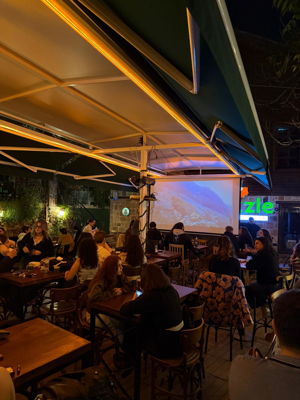 Bahçede ekran ve oturma alanı — quiz gecesi atmosferi