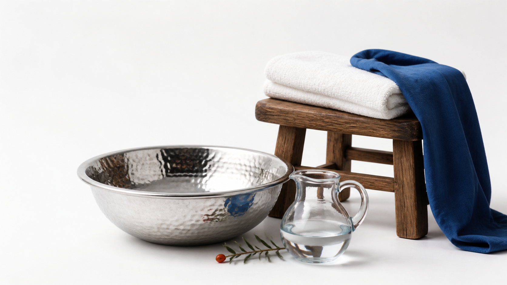 A simple wash basin with a neatly folded white towel and wooden stool on a white background