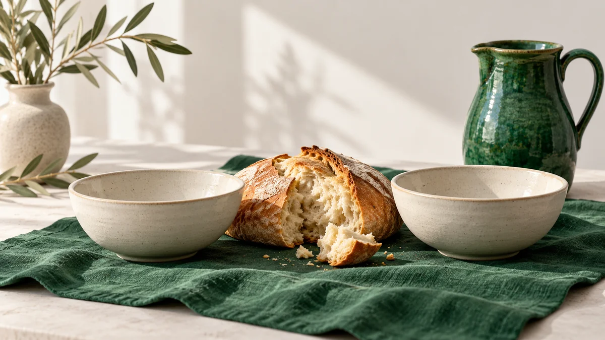 Two ivory bowls sharing bread on green linen