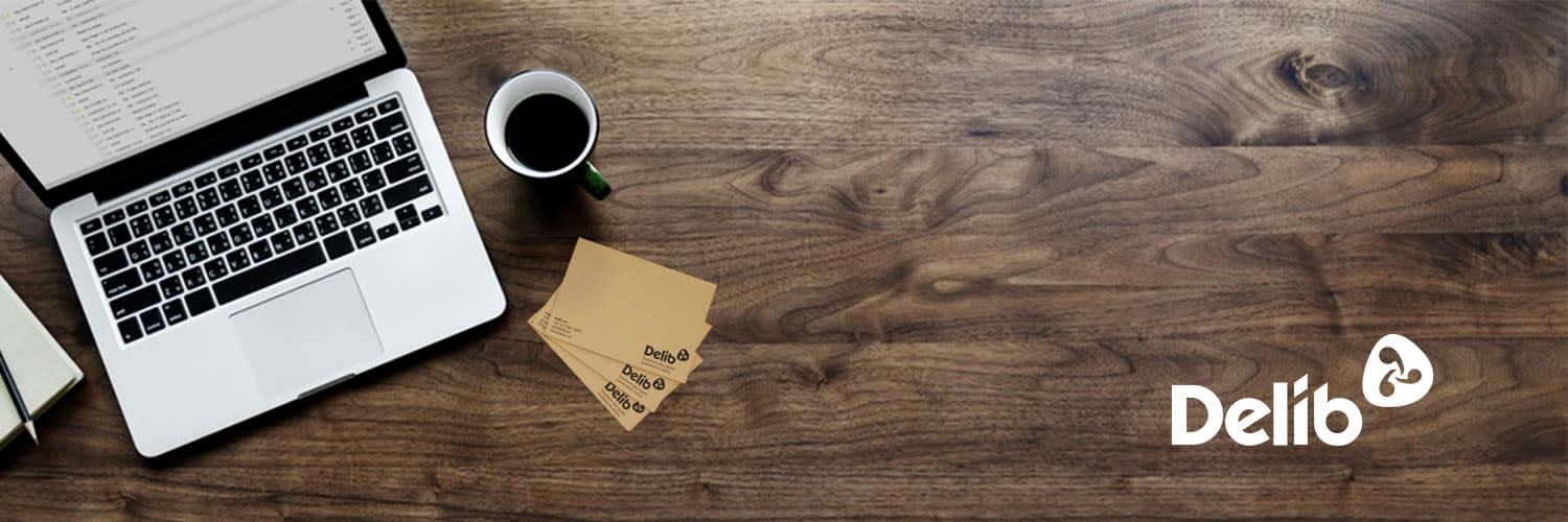 Desk with laptop, coffee mug and Delib notecards