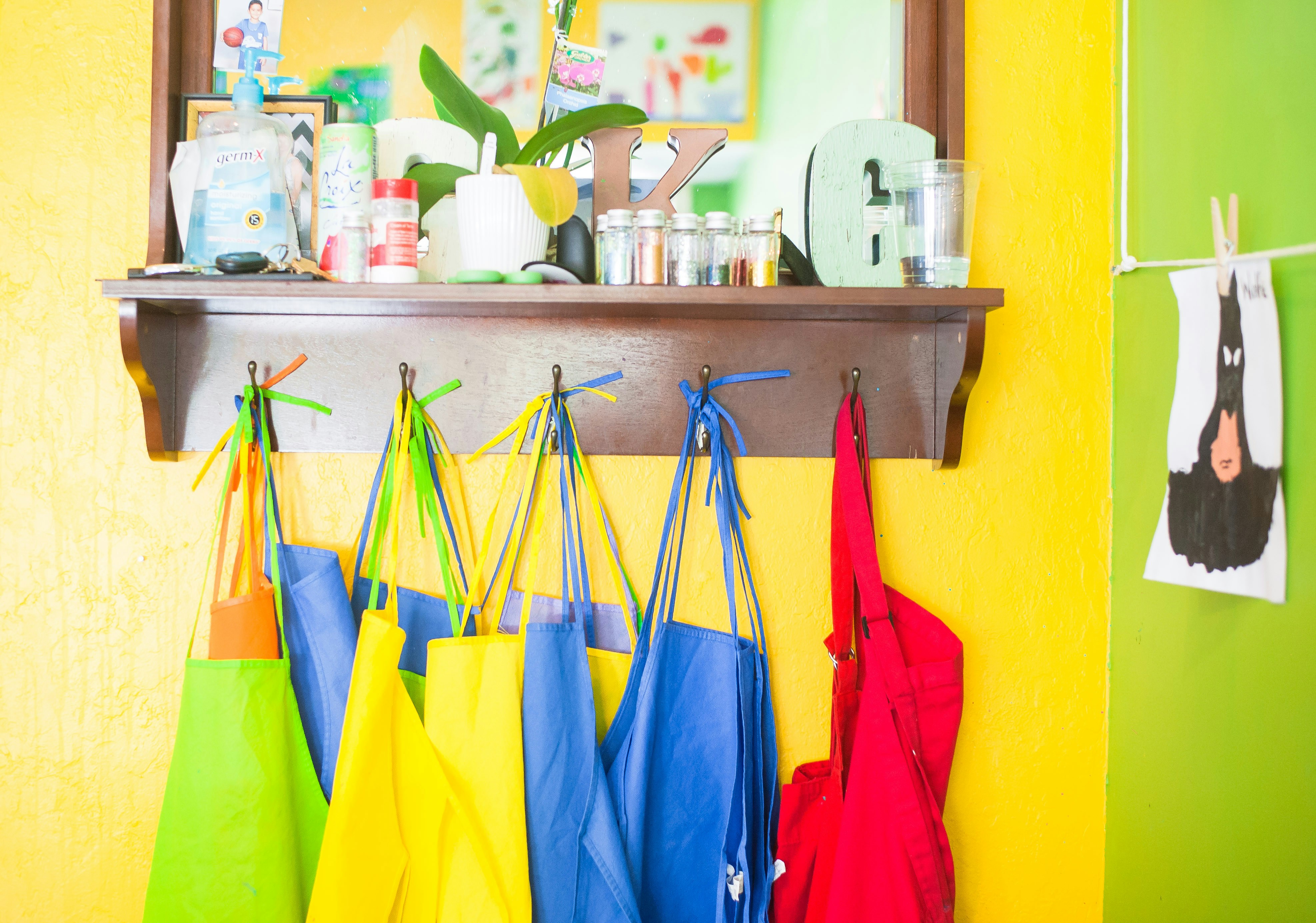 Colourful aprons hung on hooks in a school.
