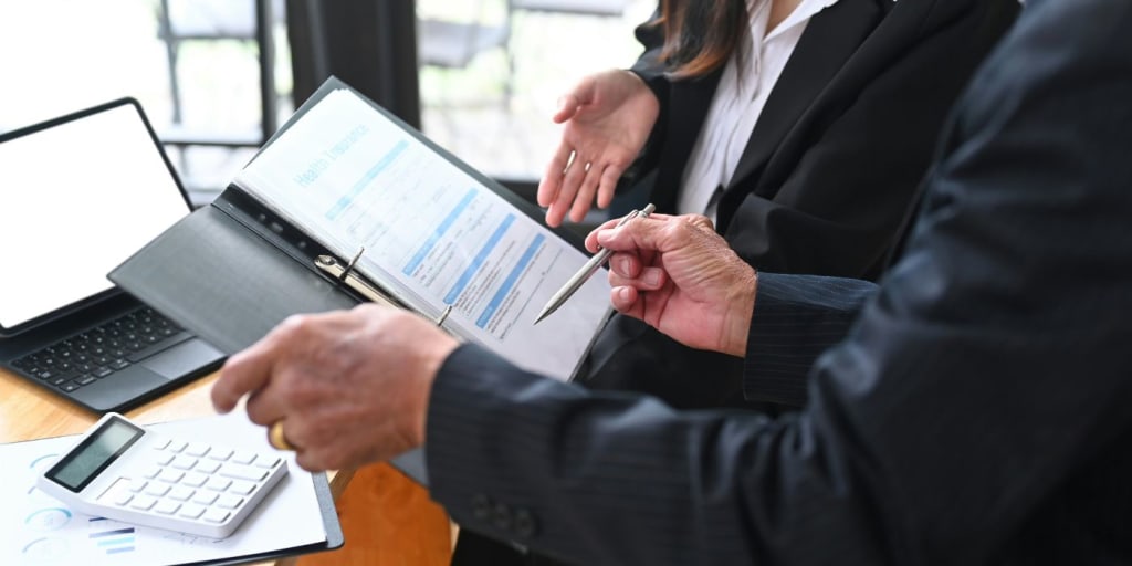 two people in suits looking at regulatory compliance documents