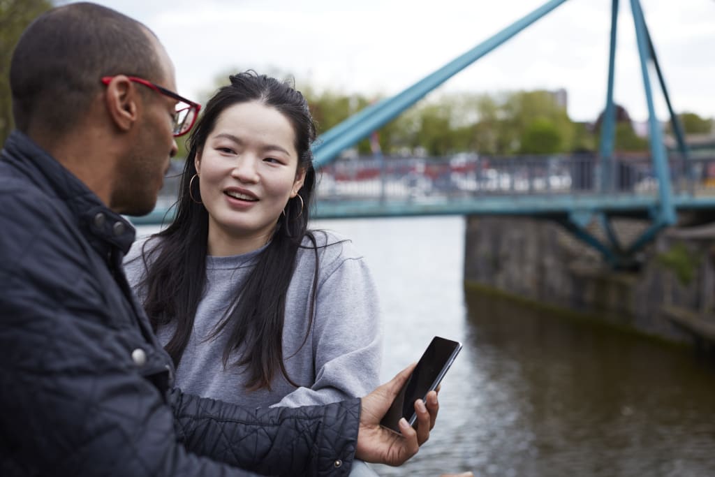 man and woman stood by river looking at phone