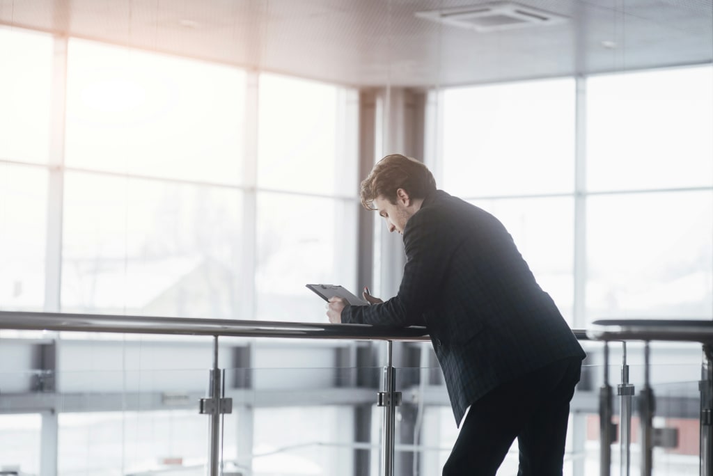 man leaning over a desk looking at a tablet