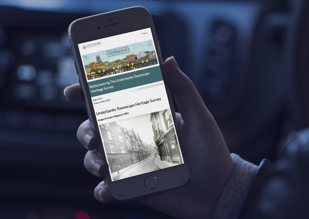 Hand holding an iPhone which displays Stockport's 'Rediscovering the Underbanks Townscape Heritage Survey'