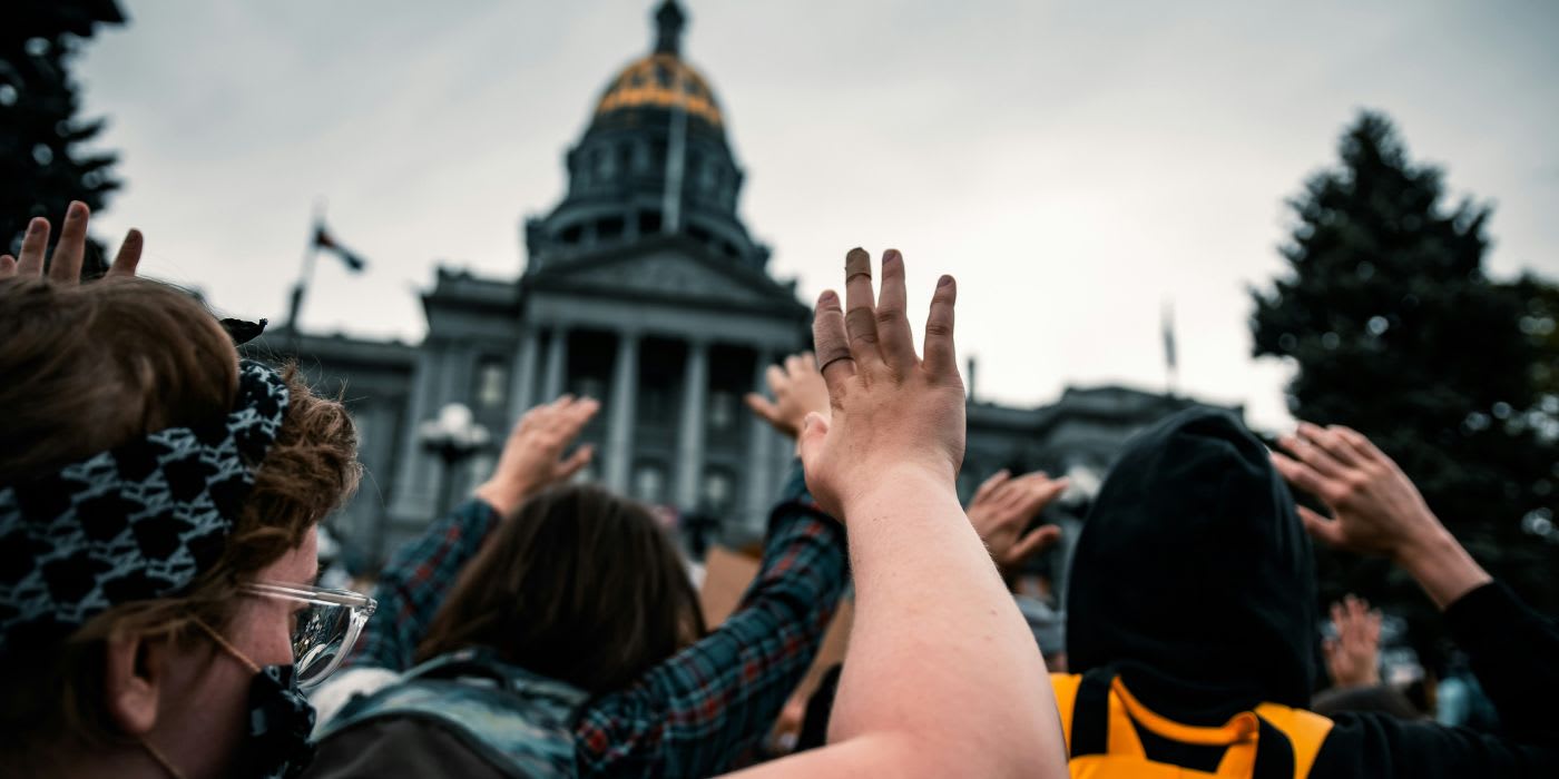 showing people with hands raised outside a government building