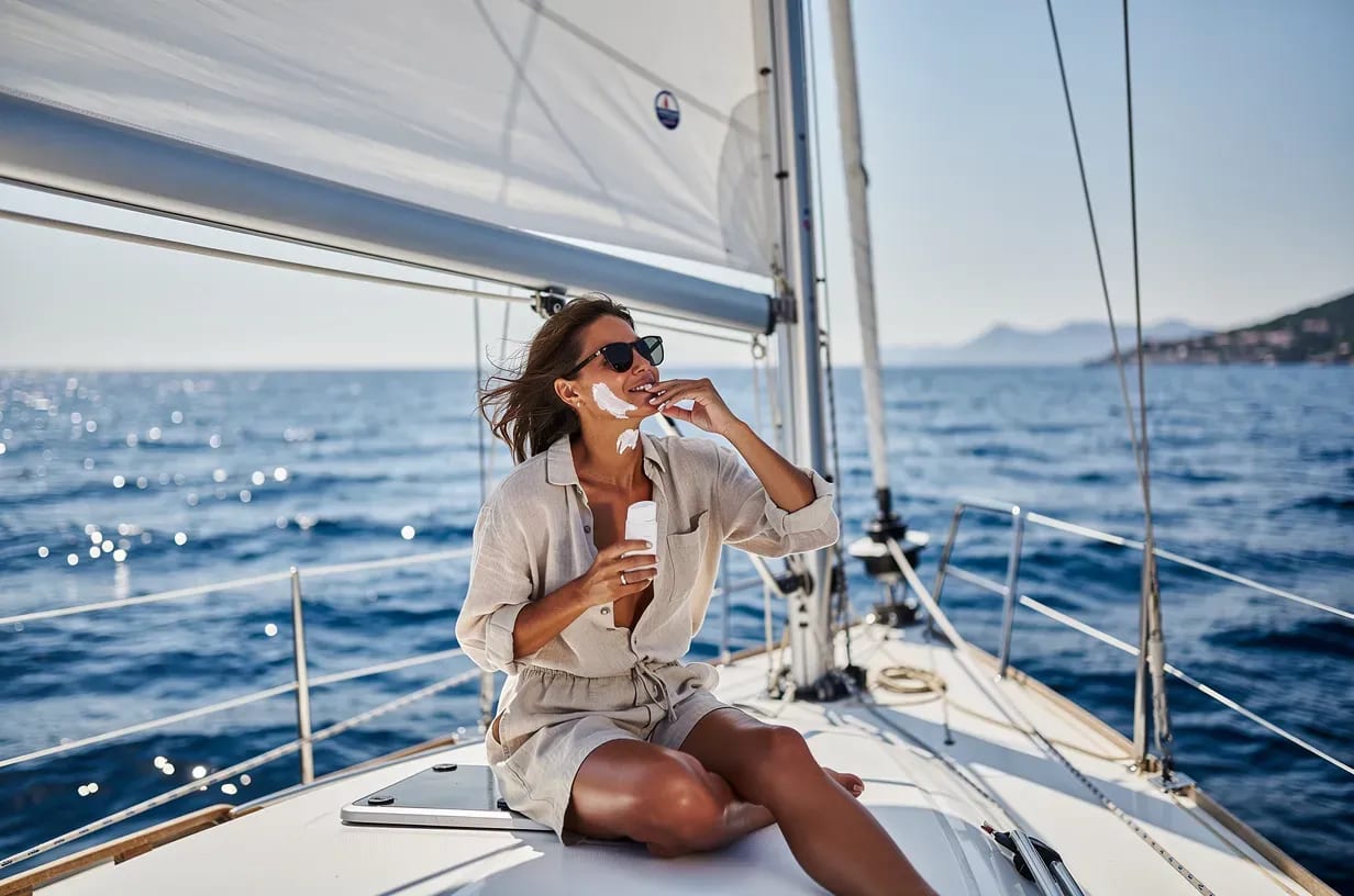 Persona aplicándose protección solar en un velero en el Mediterráneo